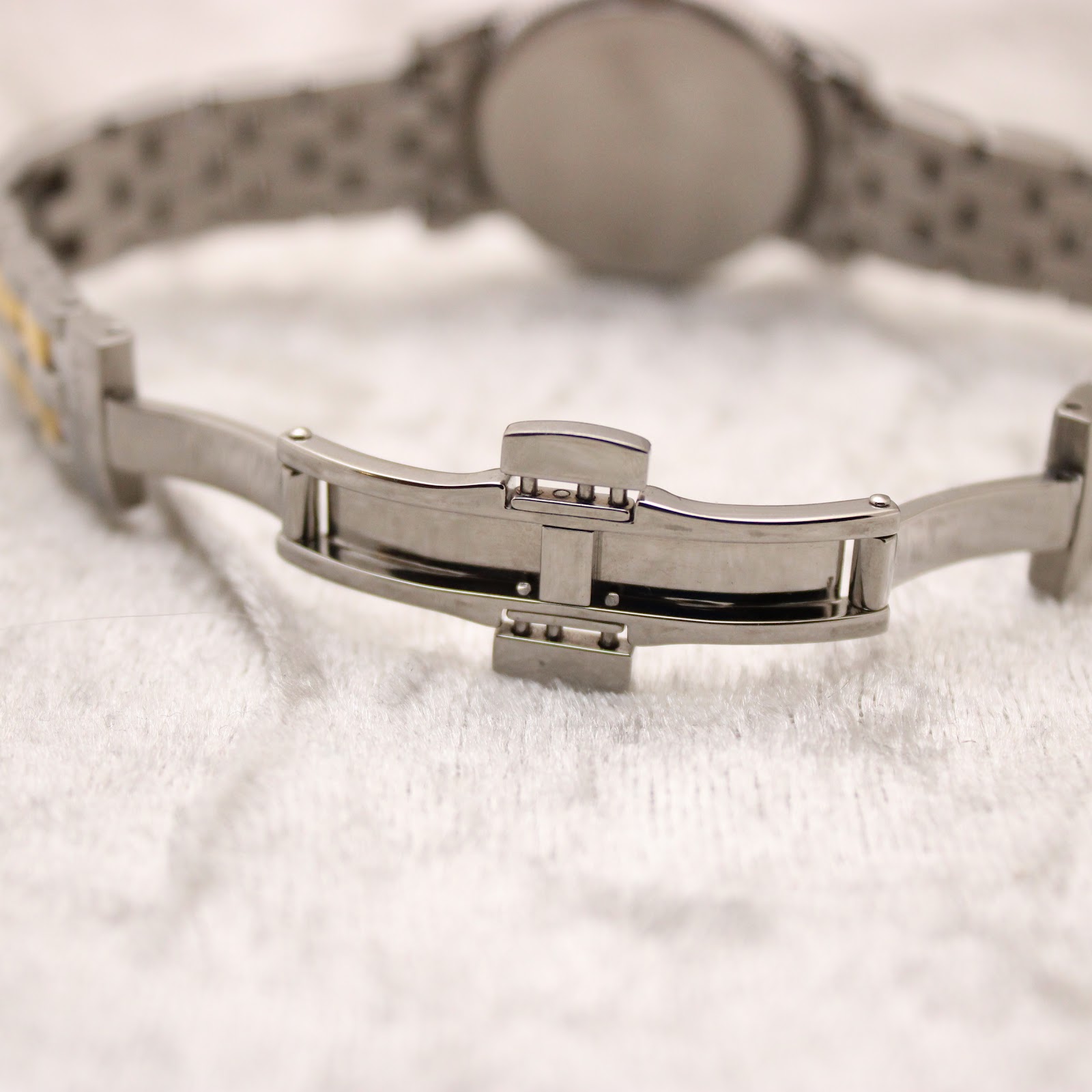 Close-up of the Tissot two-tone stainless steel bracelet with its deployant clasp open, showing interior mechanism.