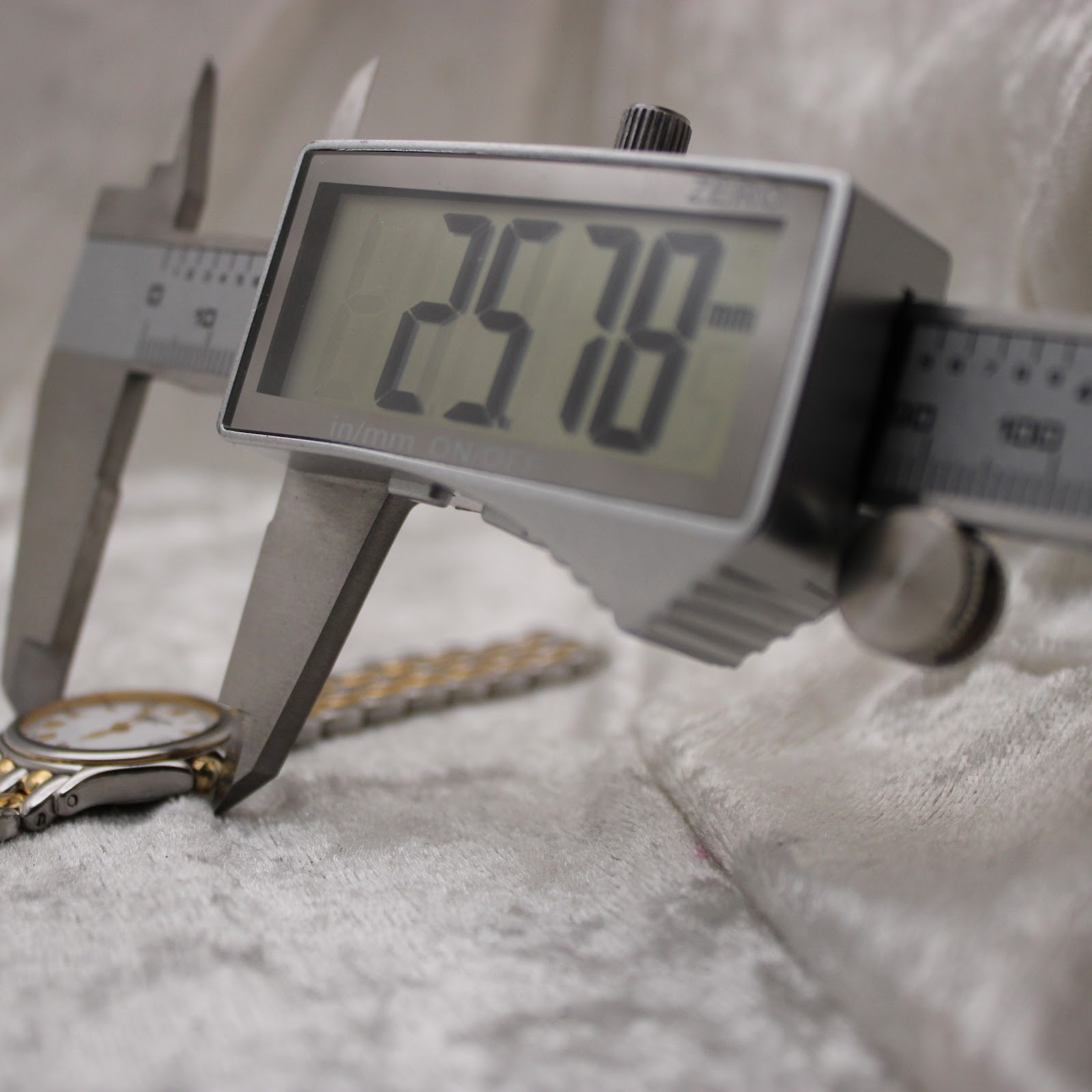 Digital caliper measuring the watch case diameter, showing a precise reading of 25.78mm.