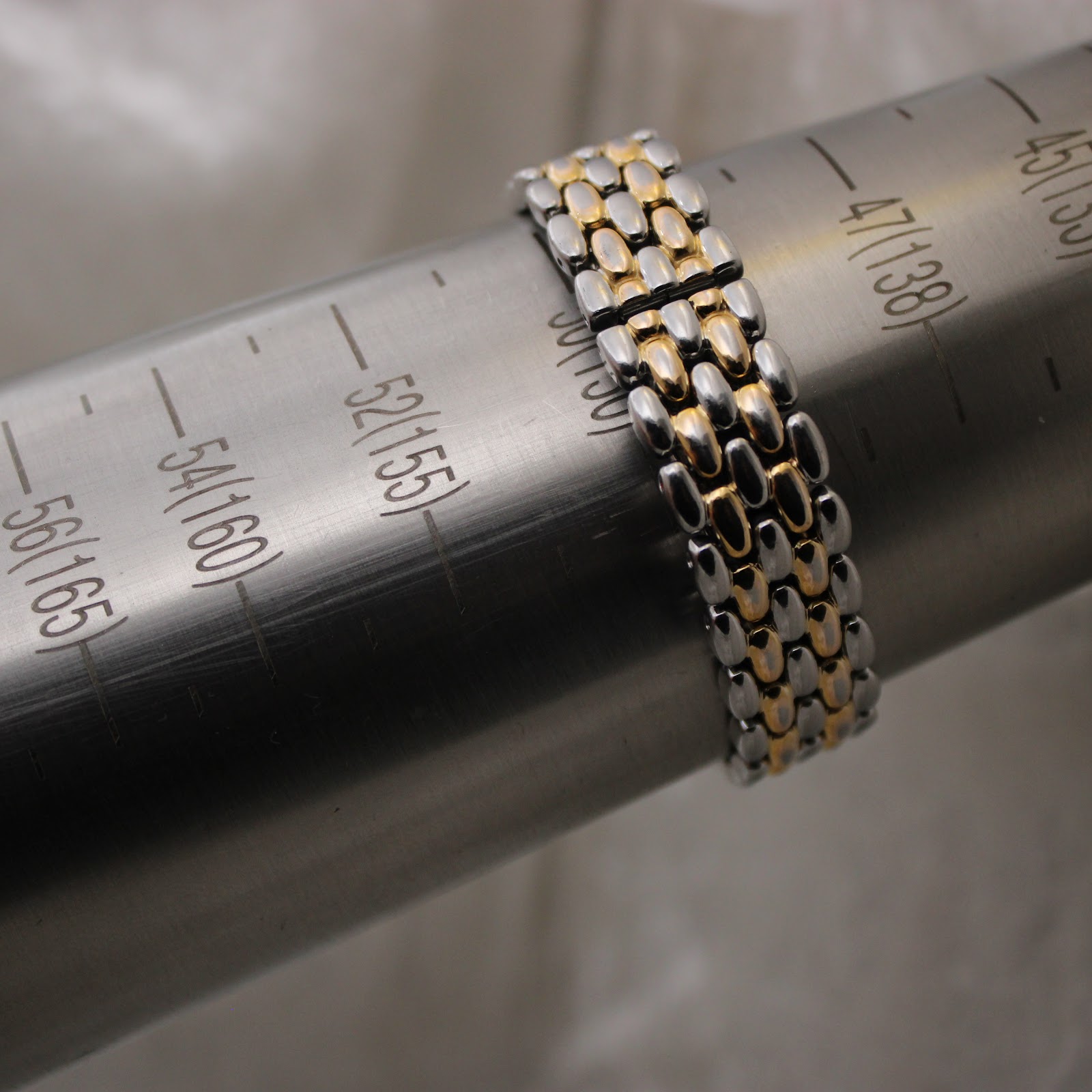 Close-up of the two-tone bracelet on a wrist sizing gauge, indicating a wrist circumference of approximately 15cm (150mm).
