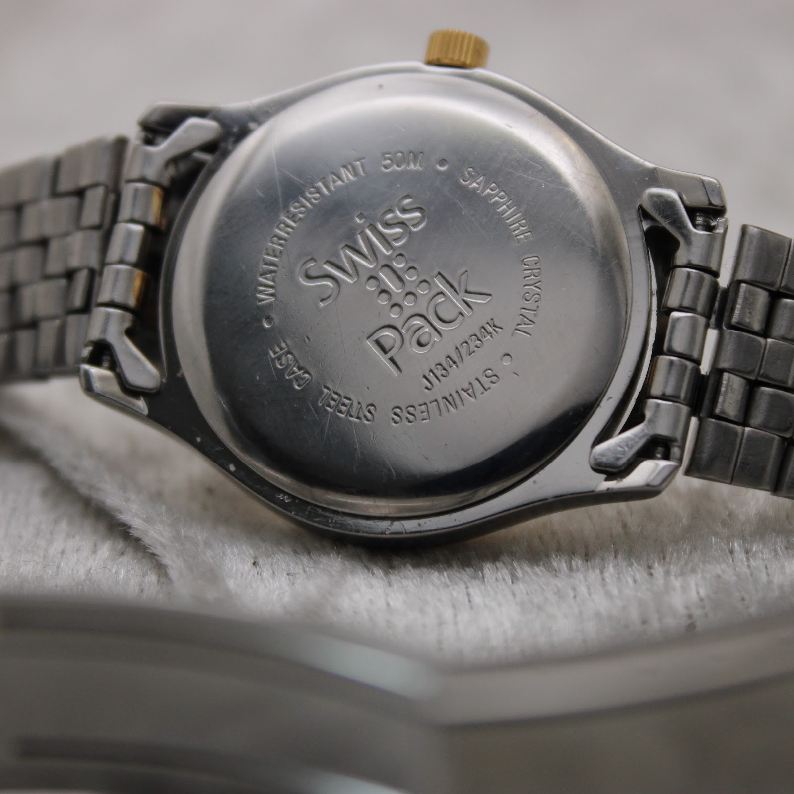 Close-up of the stainless steel case back of the Tissot PR 50, engraved with 'Swiss Pack', 'Water Resistant 50M', 'Sapphire Crystal', and model reference J134/234K.