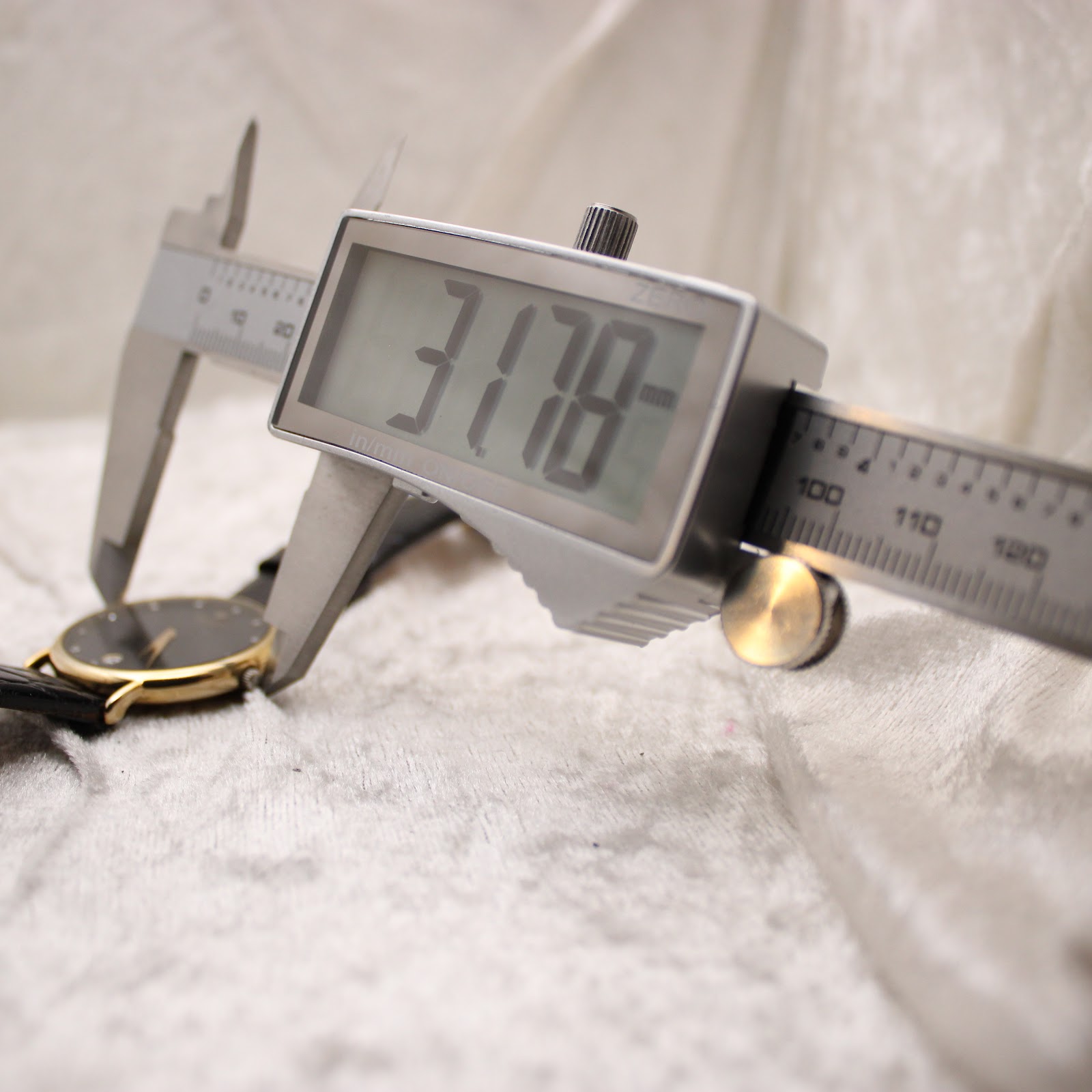 Digital caliper measuring the case diameter of the Raymond Weil watch, displaying a precise reading of 31.78mm.