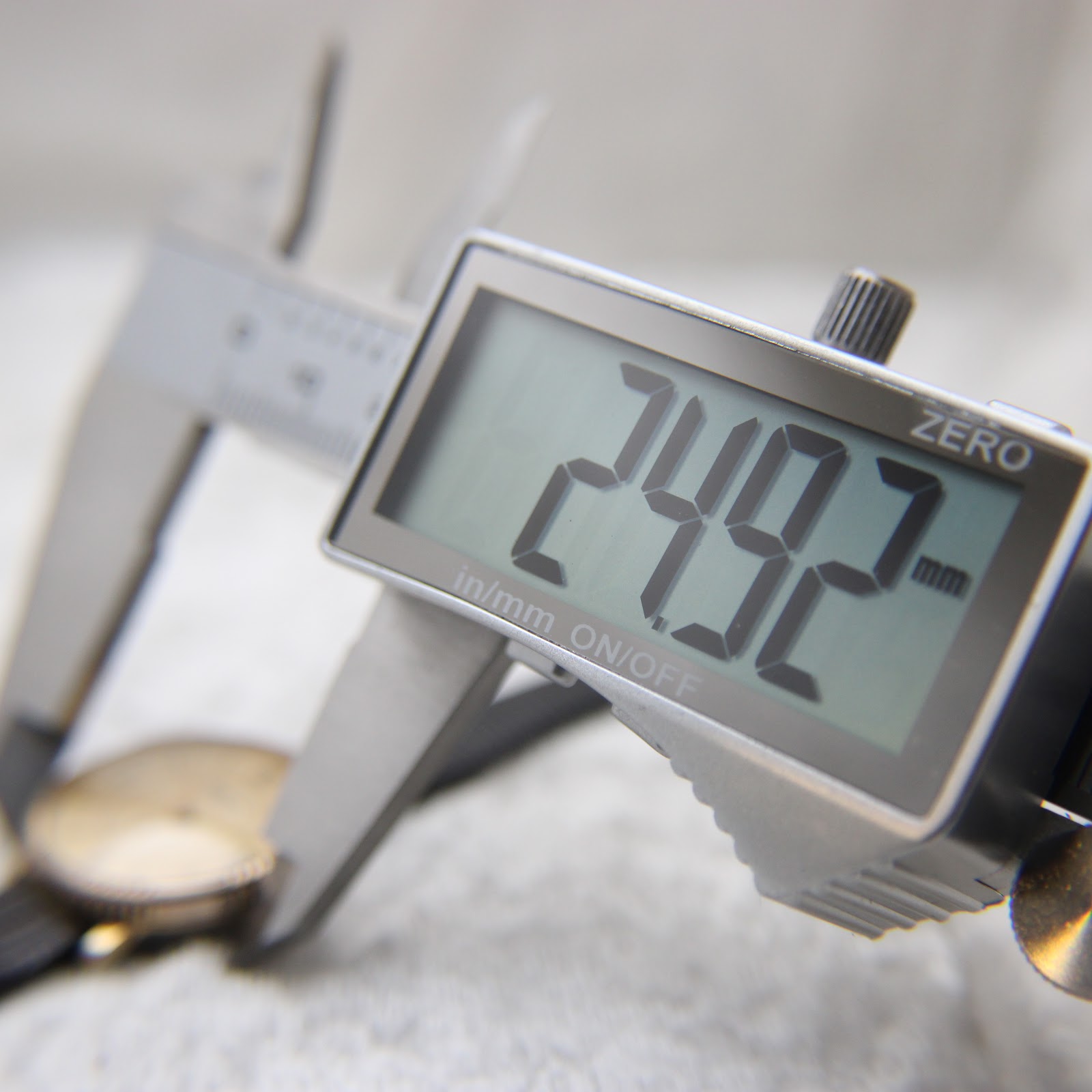 Digital caliper display showing a measurement of 24.92mm, measuring the watch case diameter.