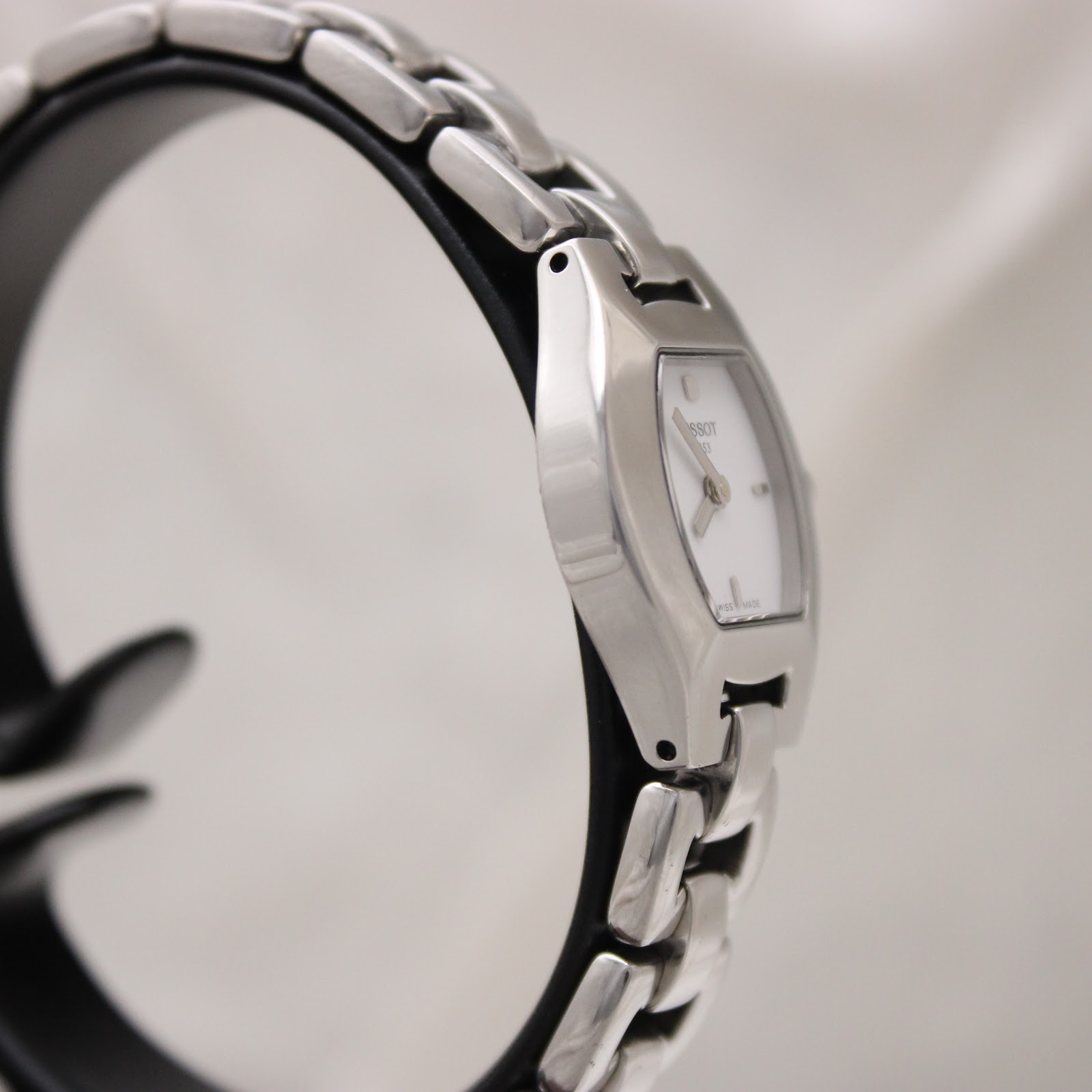 Angled side view of the Tissot G333 watch on a stand, highlighting the polished finish of the stainless steel case and bracelet.