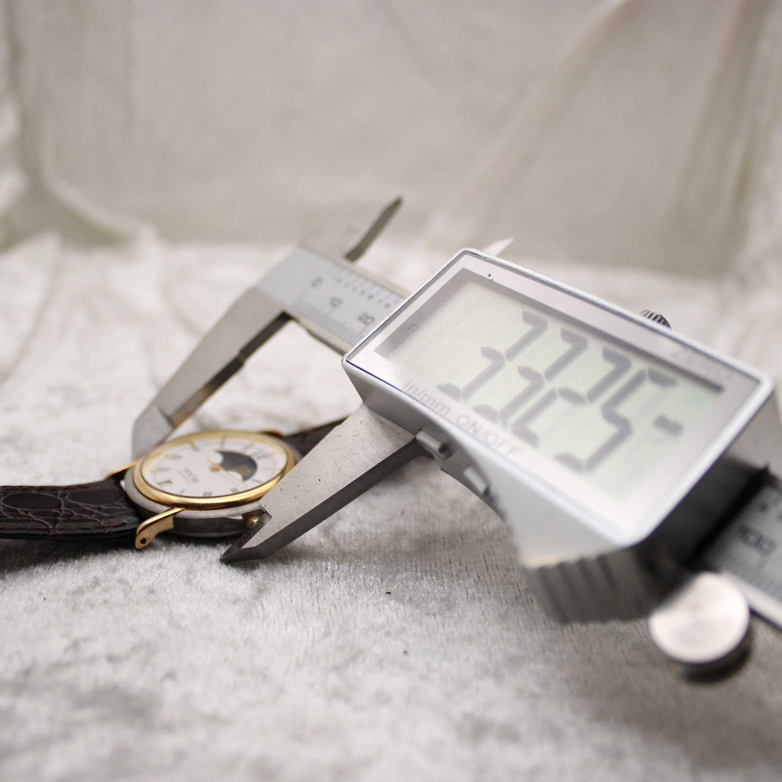 Close-up of a digital caliper measuring the watch case diameter, displaying 33.25mm.