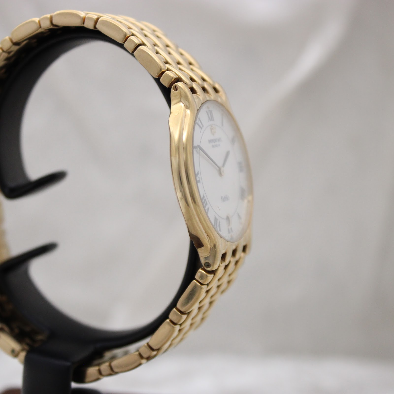 Another angled side view of the gold Raymond Weil watch highlighting the case profile and bracelet links.