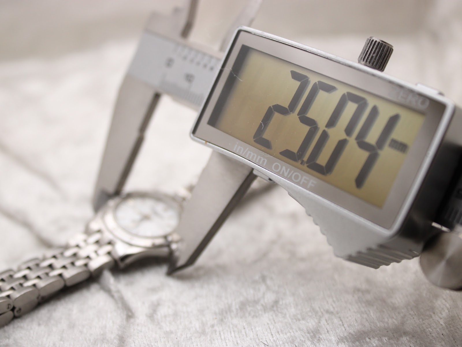 Close-up of a digital caliper measuring the watch case, displaying a precise diameter of 25.04 mm.