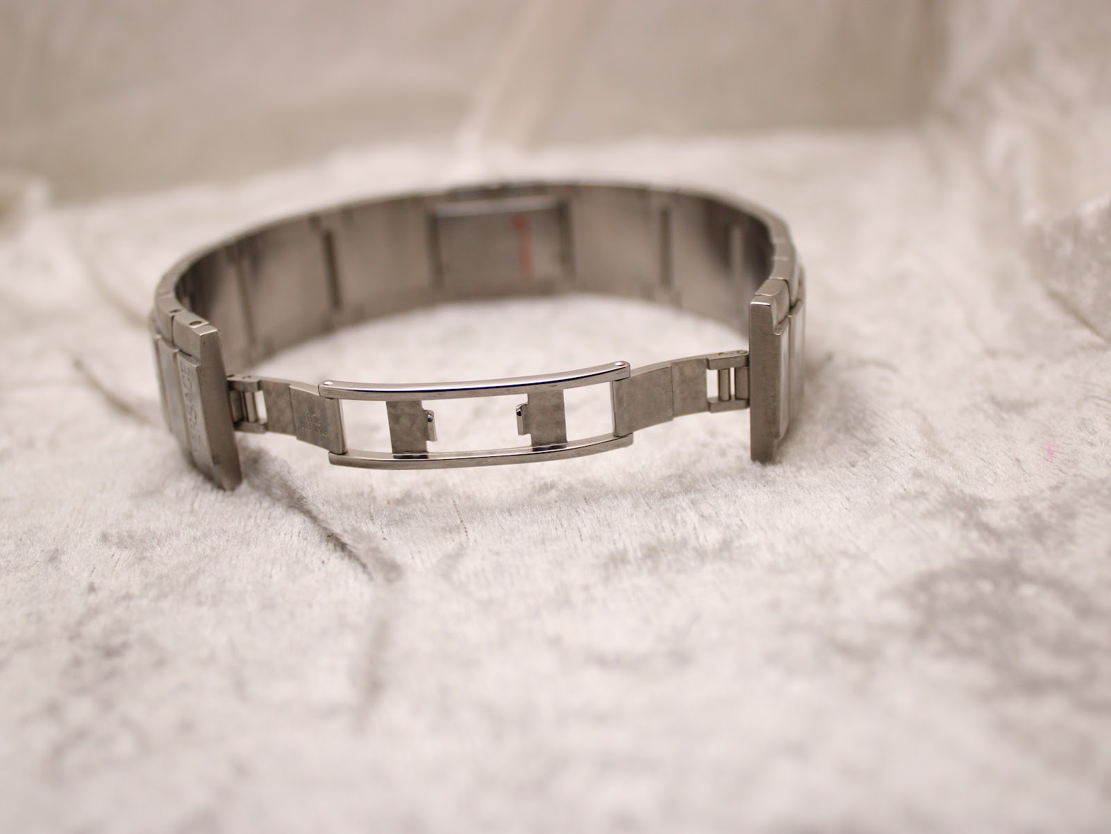 Underside view of the stainless steel greca bracelet with its deployment clasp open.