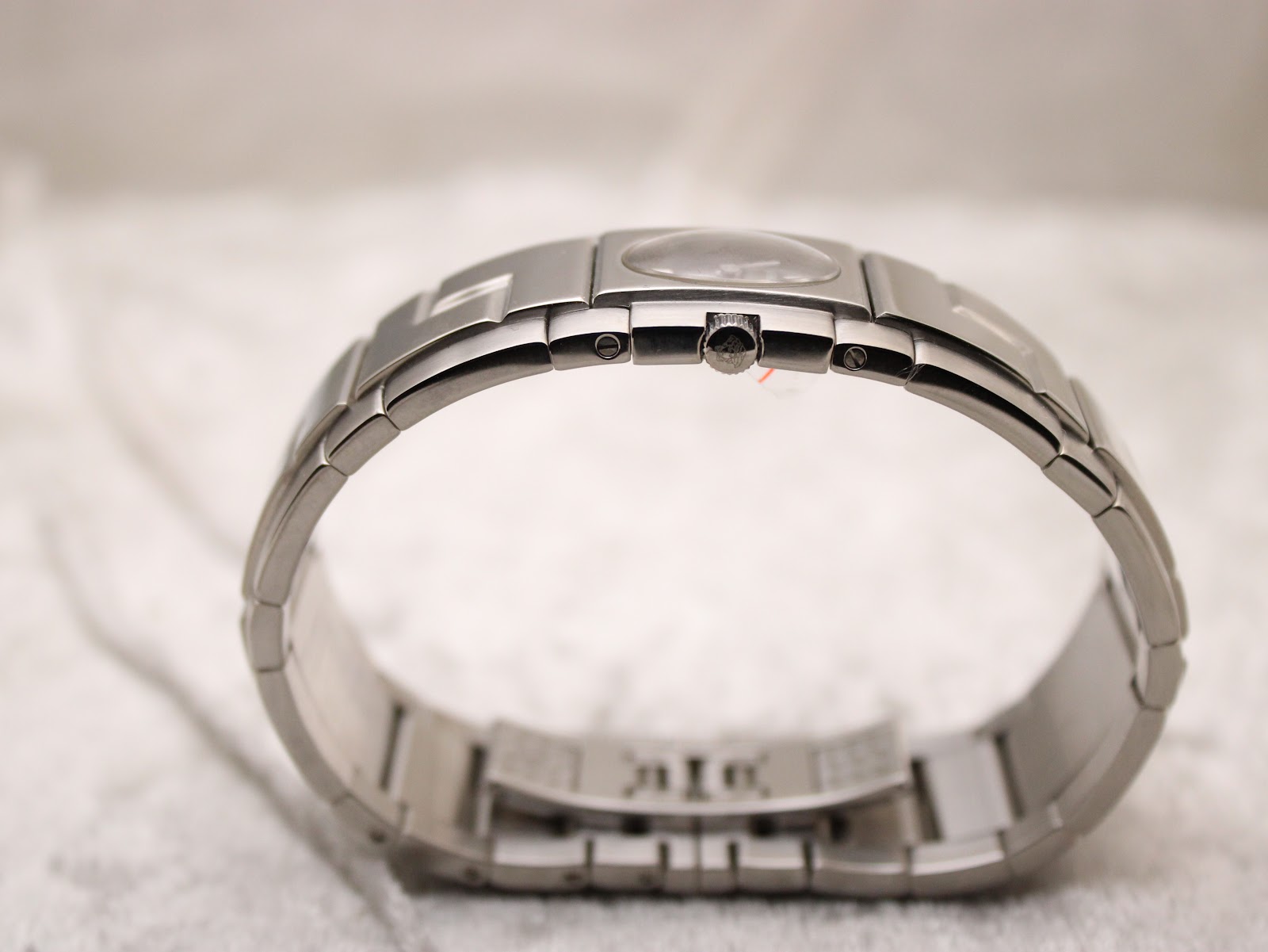 Angled view of the watch on a stand, showcasing the full circumference of the stainless steel bracelet.