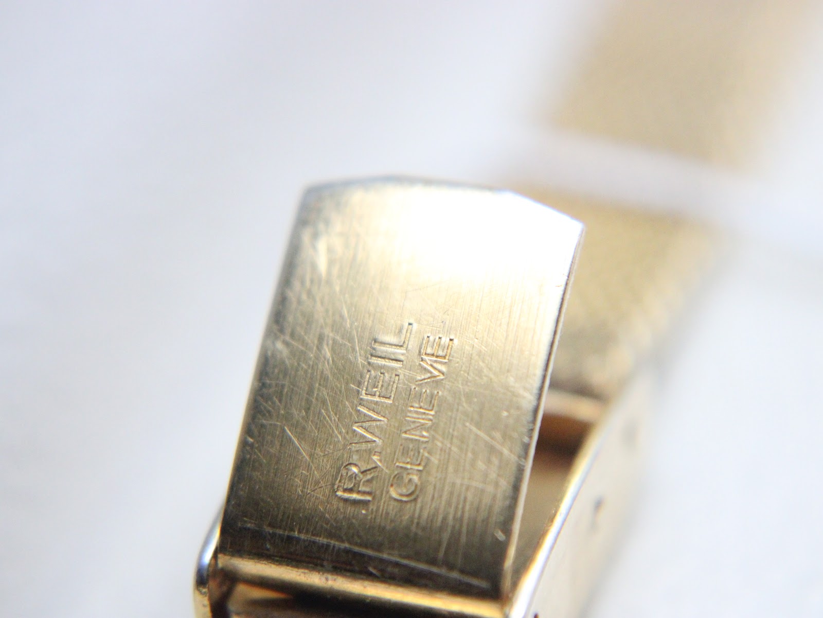 Close-up of the gold-tone clasp, clearly showing the 'R. WEIL GENEVE' signature engraving.
