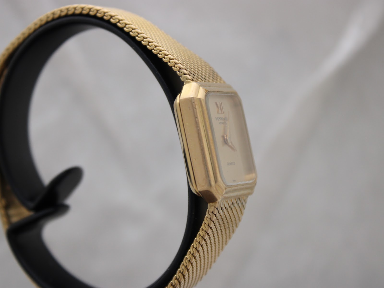 Another side view of the gold-plated watch, highlighting the slim profile and mesh bracelet texture.