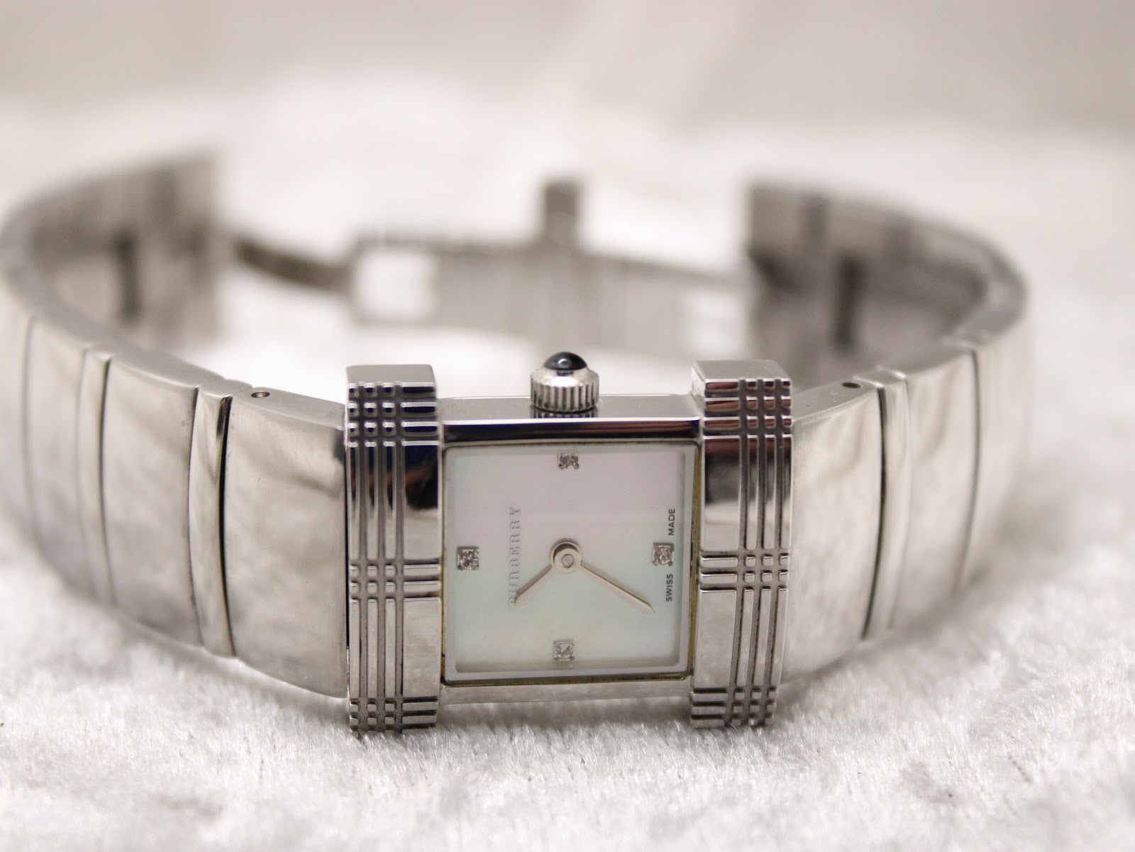 Full view of the Burberry watch laid open, displaying the integrated silver-tone bracelet and rectangular dial.