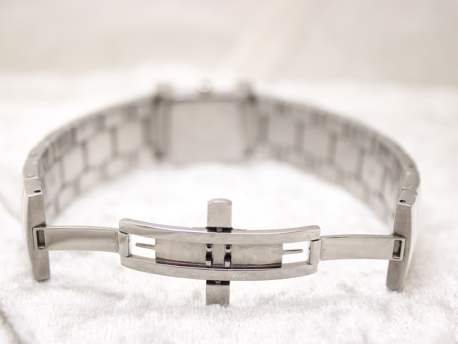 Close-up of the watch's hidden butterfly clasp, made of polished silver-tone metal.
