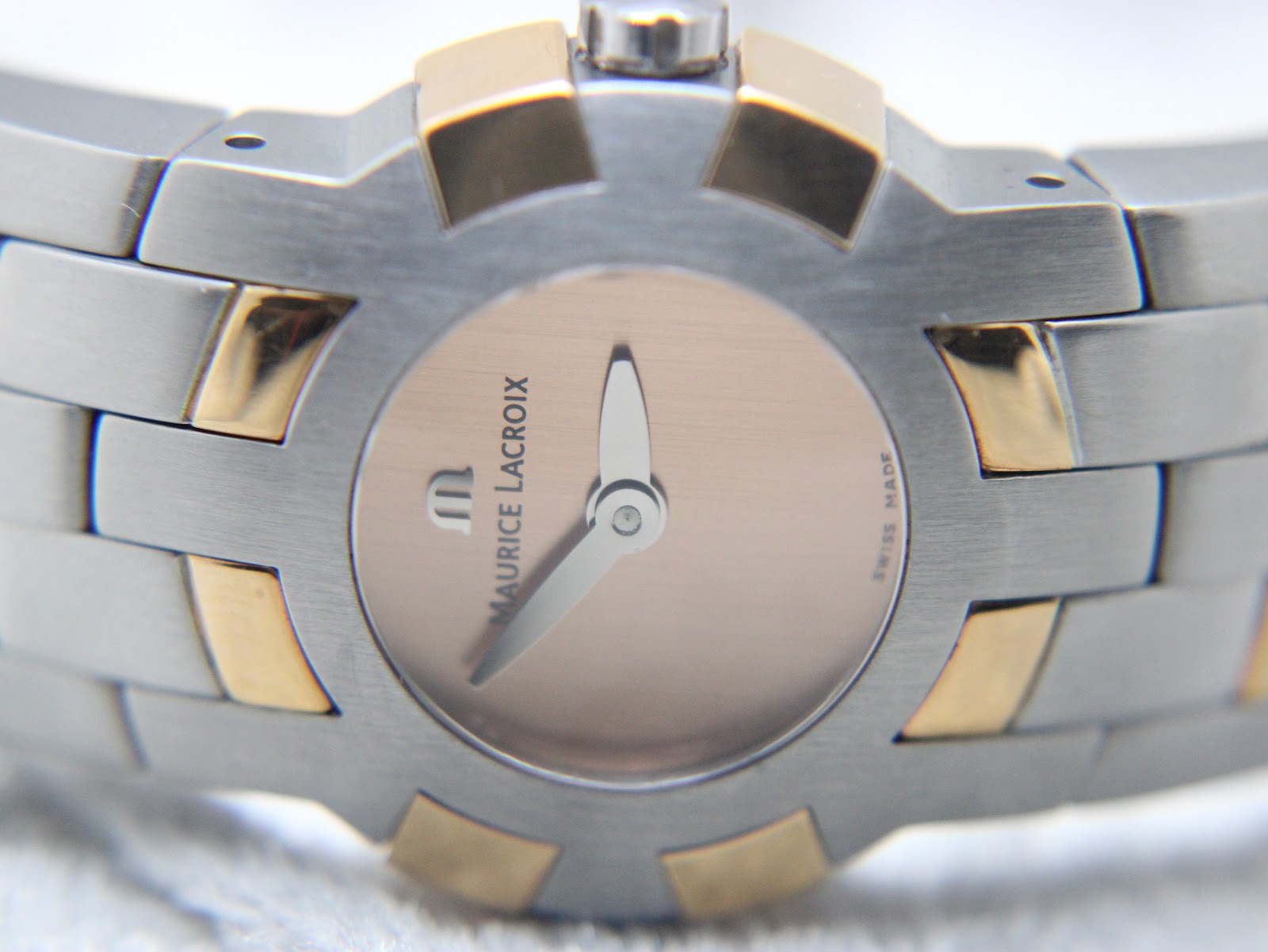Close-up of the minimalist pink dial with silver-tone baton hands and 'MAURICE LACROIX SWISS MADE' text.