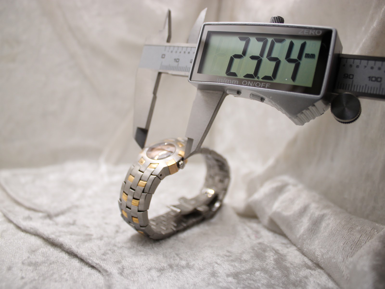 Digital caliper measuring the case diameter of the watch, showing a precise reading of 23.54mm.
