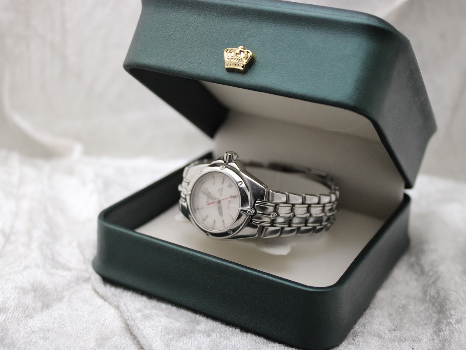 The Tissot PR 200 watch displayed in a dark green presentation box with a gold crown emblem on the lid.