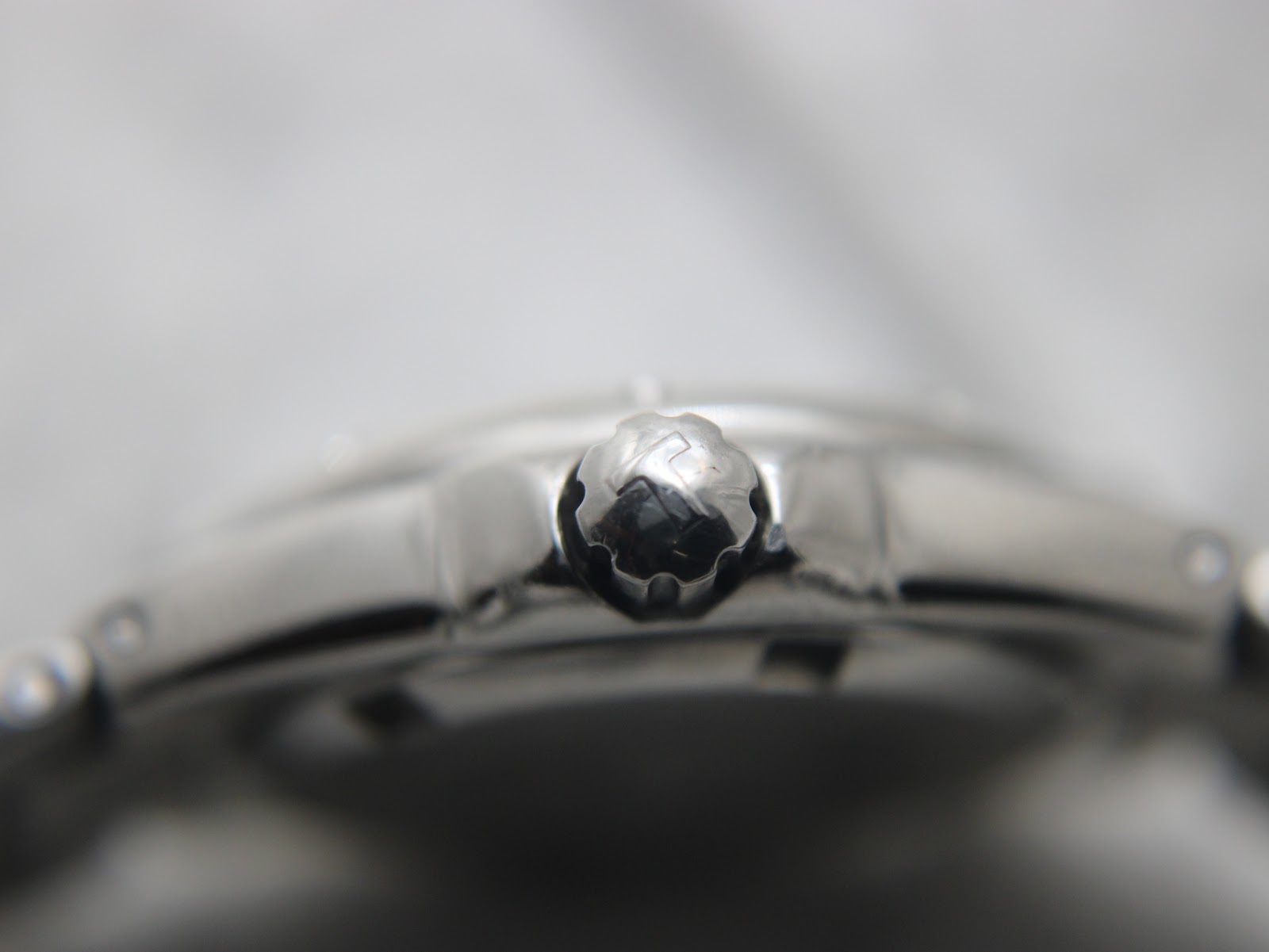 Extreme close-up of the signed "T" logo crown on the Tissot PR 200 watch, indicating its brand heritage.