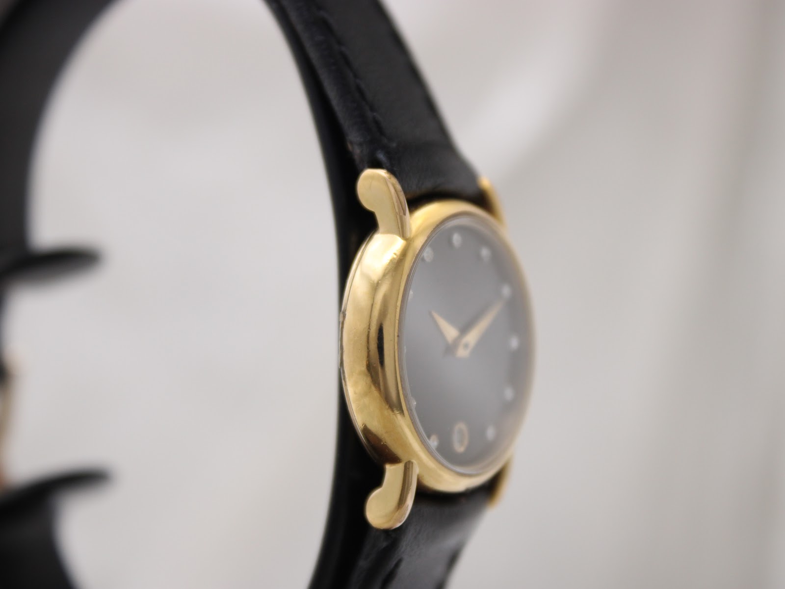 Close-up of black genuine leather strap and gold buckle.
