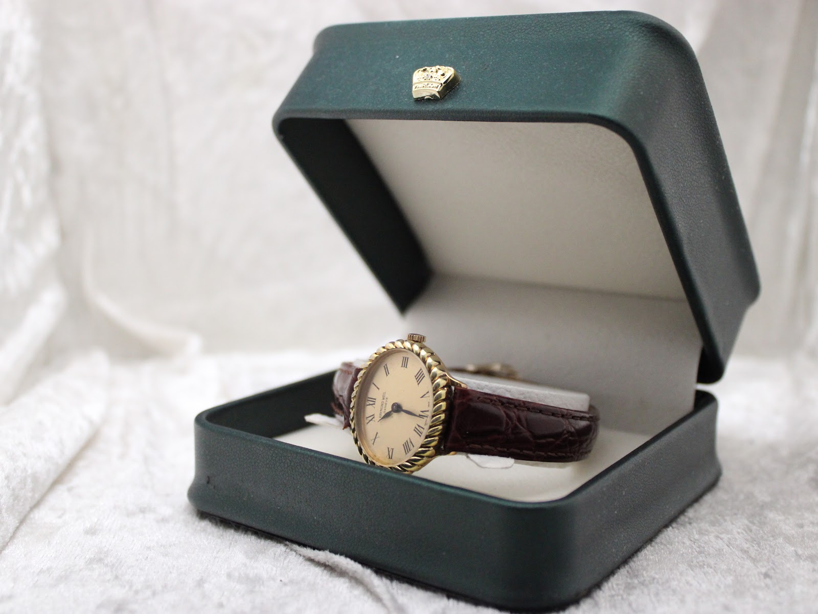 Raymond Weil 683 watch presented in an open dark green presentation box with a crown emblem on the lid.