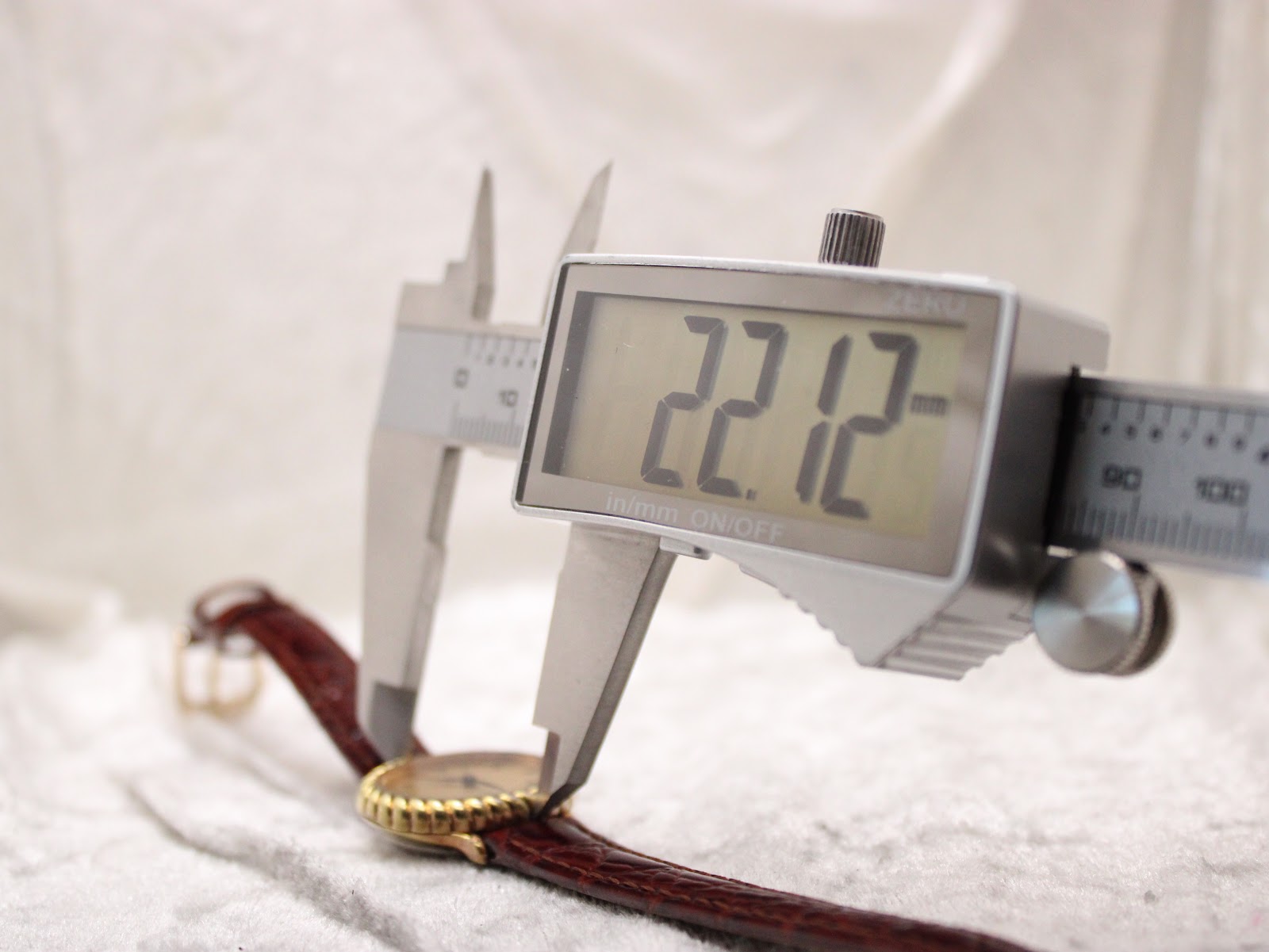 Digital caliper measuring the case width of the watch, displaying a precise measurement of 22.12mm.
