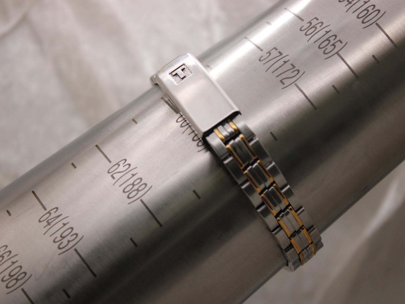 Two-tone bracelet of the Tissot PR 50 watch on a wrist sizing gauge, indicating a fit of approximately 180mm.
