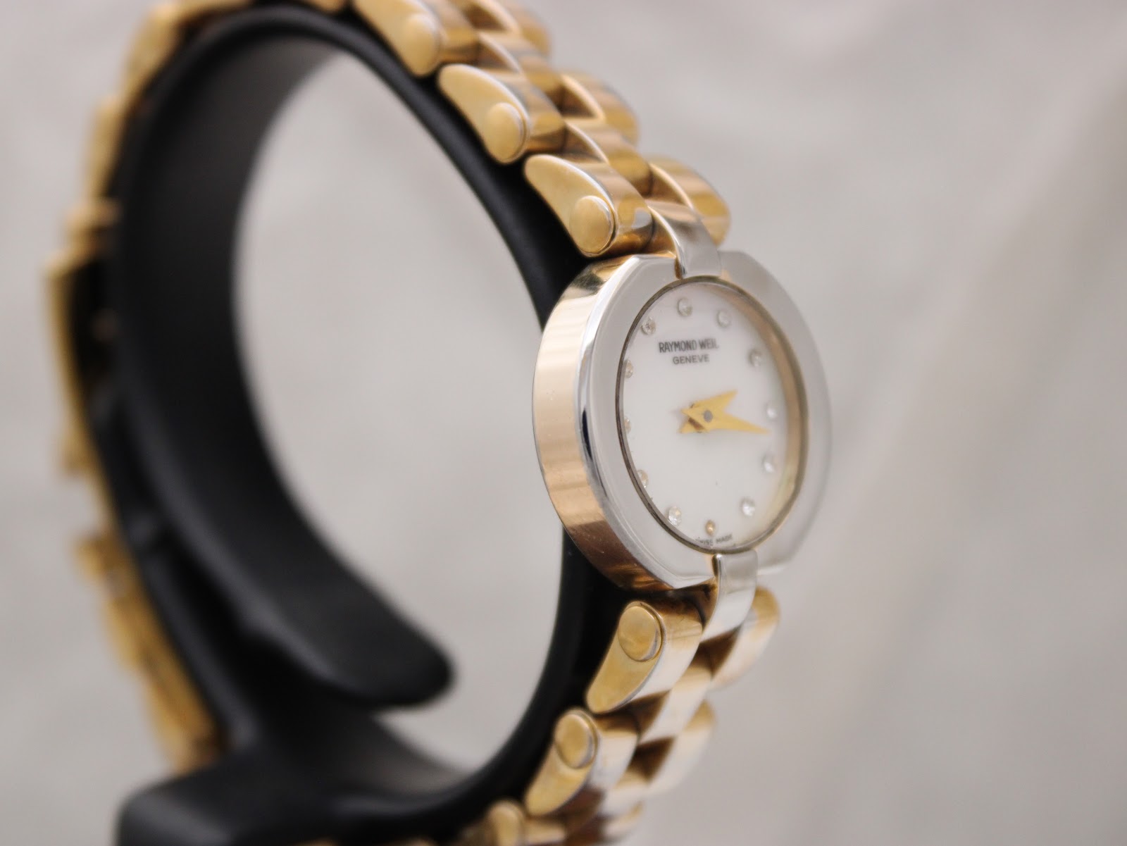Angled side view of Raymond Weil watch, highlighting the polished bezel and two-tone bracelet