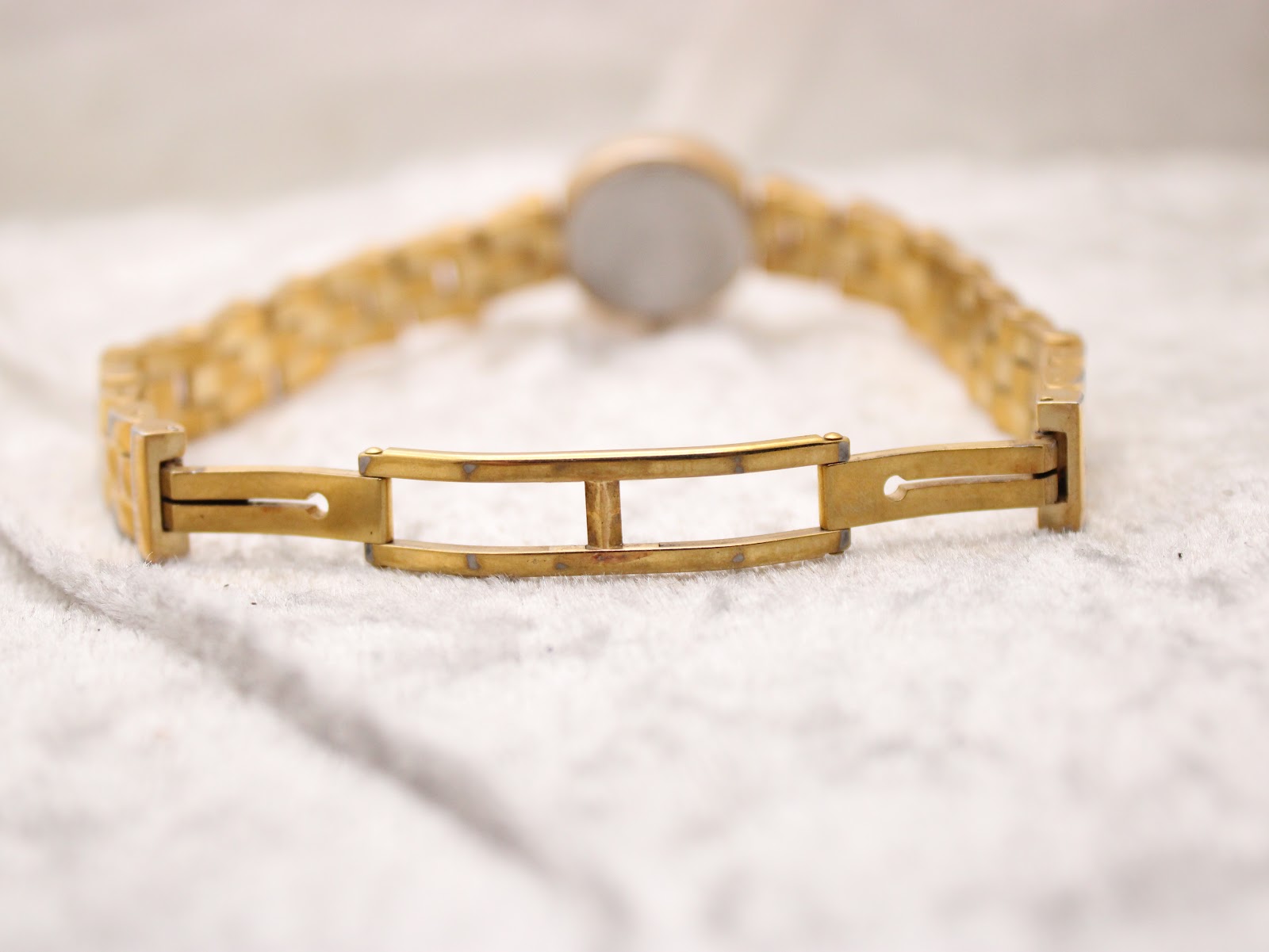 Rear view of the watch bracelet's folded clasp mechanism, showing some gold-tone wear