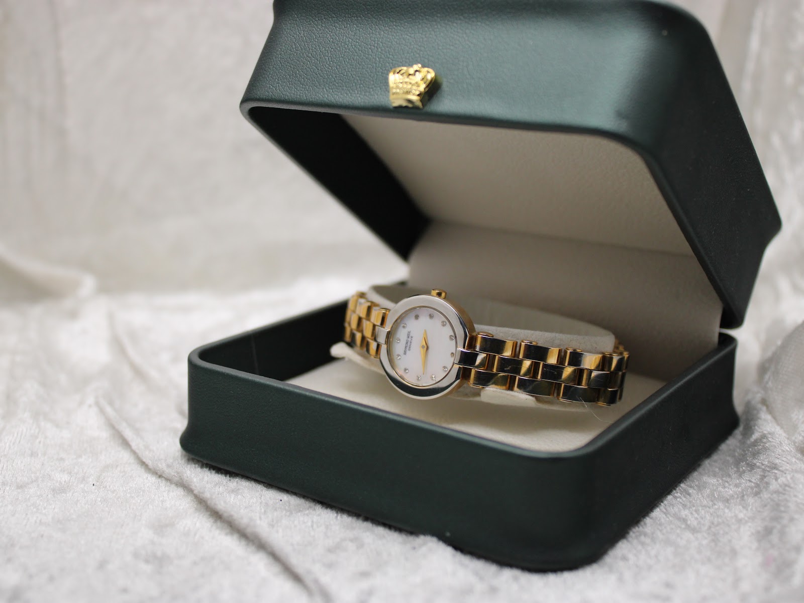 Raymond Weil watch presented inside a dark green display box with a small gold crown detail