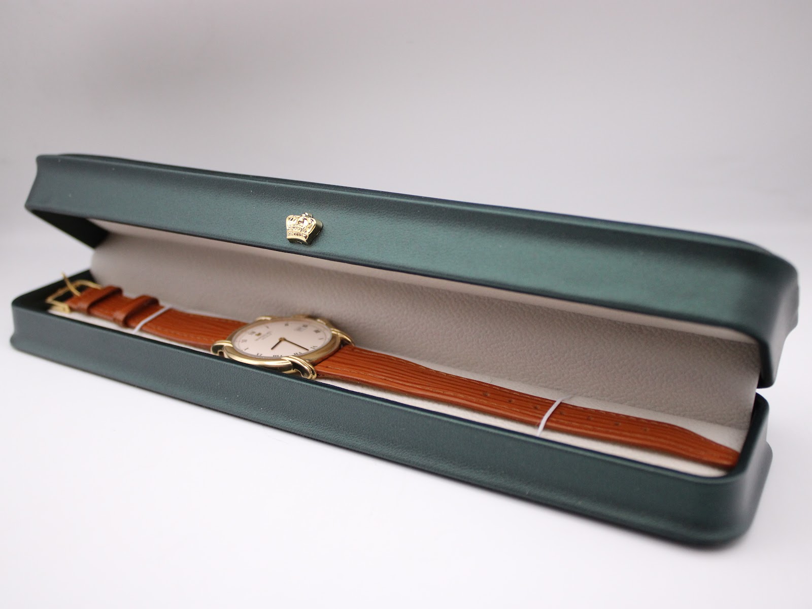 The Raymond Weil 9155 watch with its brown leather strap presented inside a dark green display box.