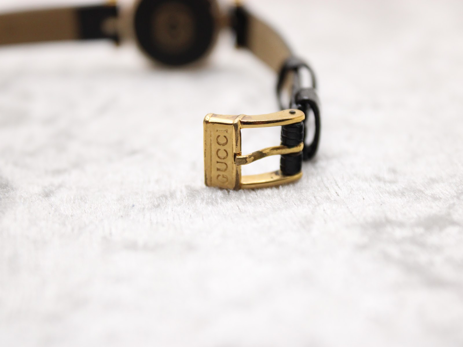 Close-up of the gold-tone pin buckle of the Gucci 2000L, clearly signed with the 'GUCCI' logo.