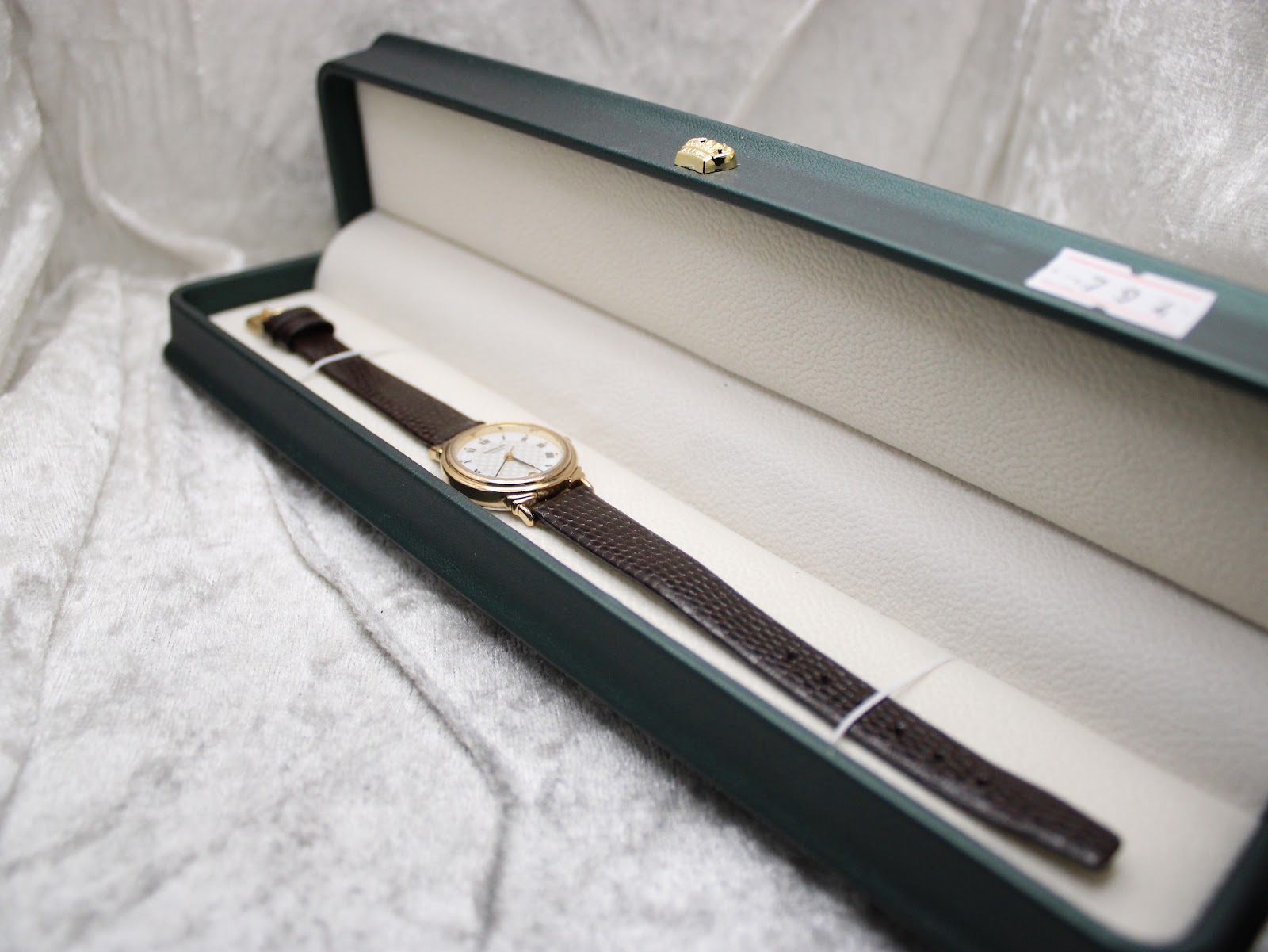Angled view of the Raymond Weil 5331 watch lying inside a dark green presentation box.