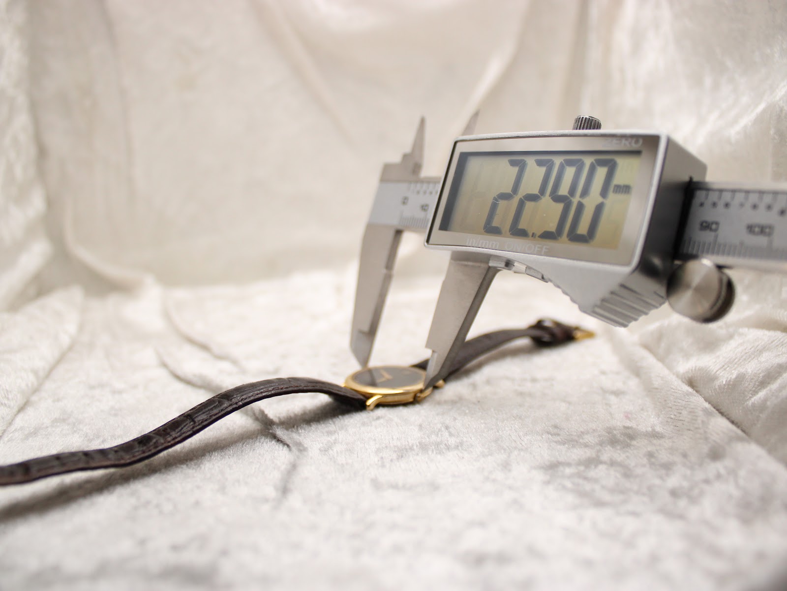 Digital caliper measuring the case diameter of the Raymond Weil watch, displaying 22.90mm.