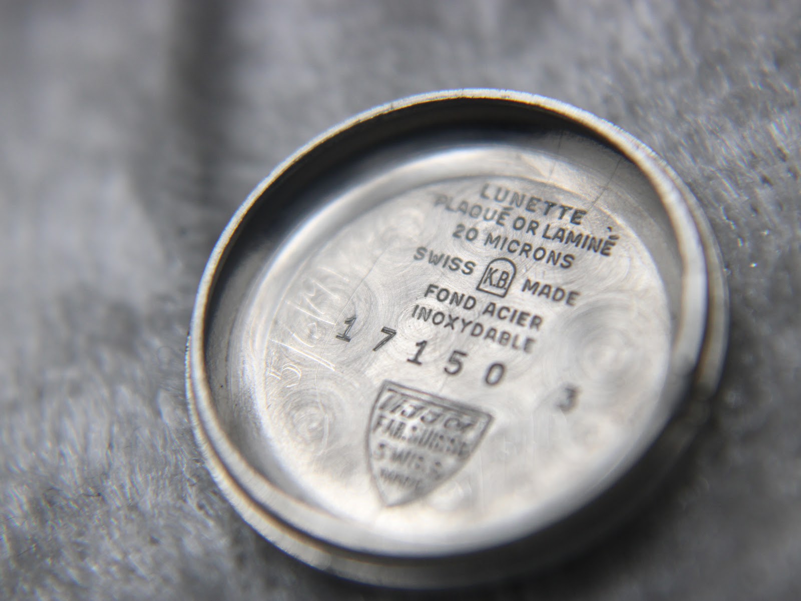Interior view of the watch case back, showing markings like "20 MICRONS", "SWISS MADE", "17150", and the Tissot logo.