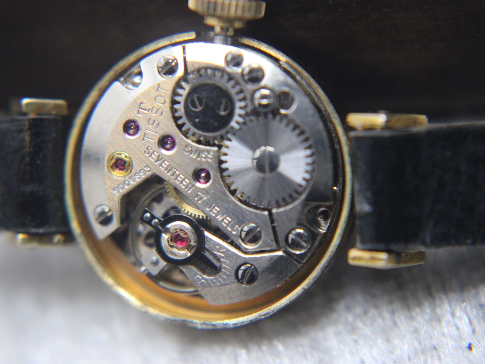 Macro shot of the 17-jewel Swiss manual wind mechanical movement, revealing gears, ruby jewels, and the Tissot calibre marking.