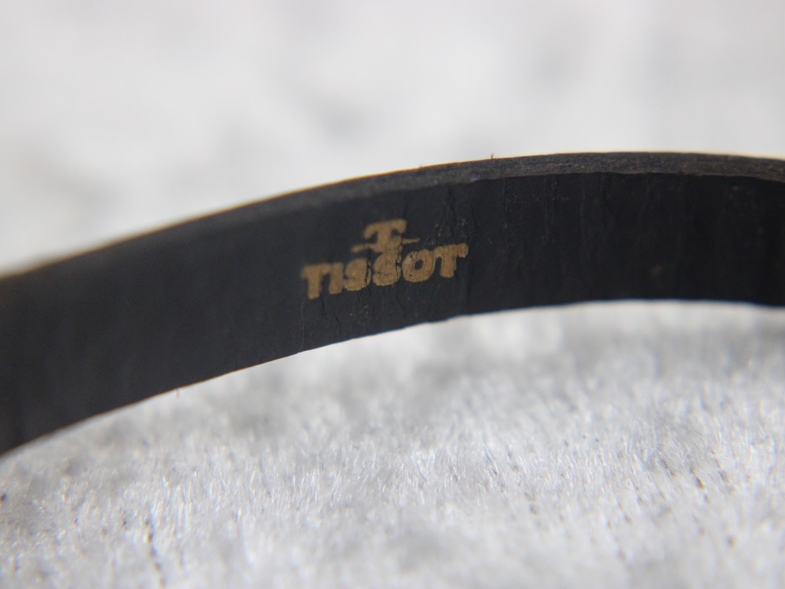 Detail shot of the interior of the black leather strap, clearly showing the embossed gold 'Tissot' logo.