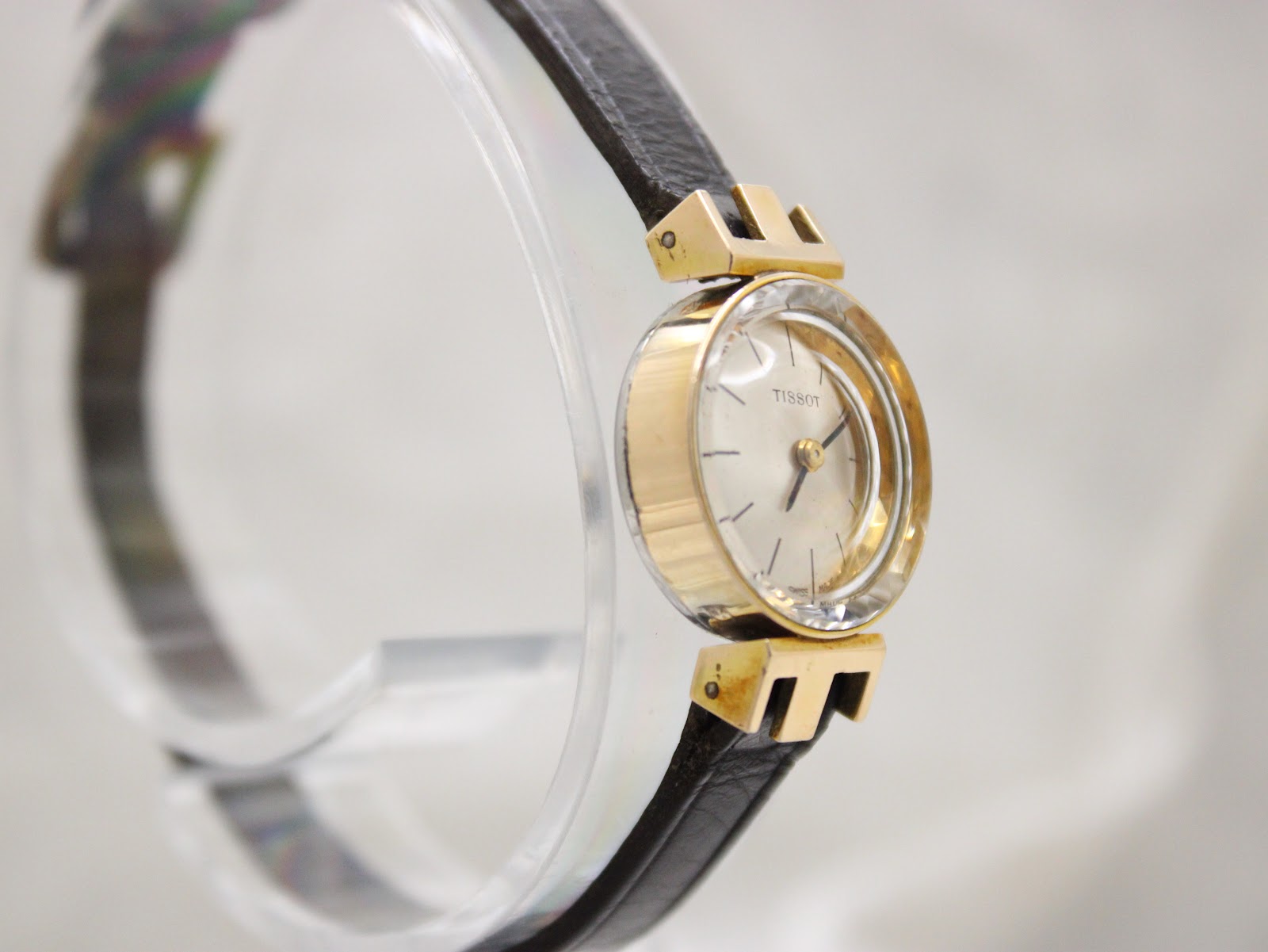 Oblique view of the Tissot watch from the left, showcasing the elegant case profile and the integrated strap design.