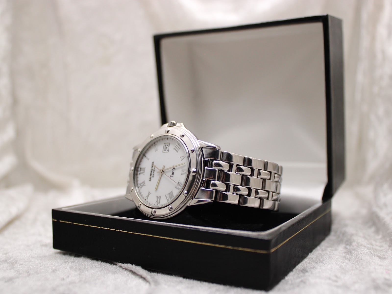 Raymond Weil Tango 5560 watch resting inside an open black presentation box with a white interior.
