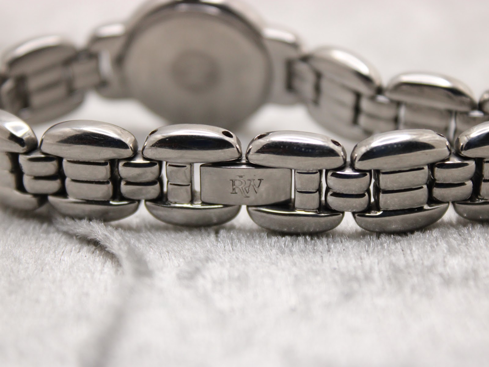 Close-up of the Raymond Weil stainless steel bracelet clasp, clearly showing the engraved 'RW' logo.