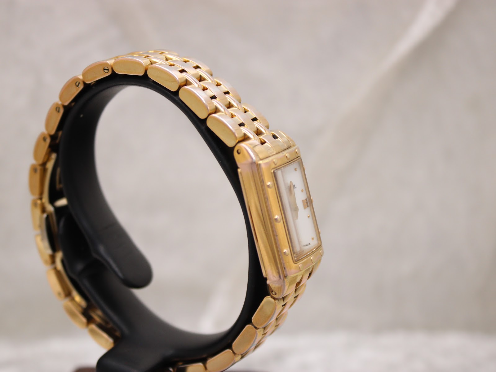 Angled side view of the Raymond Weil Tango watch on a black stand, showcasing the case and bracelet design.