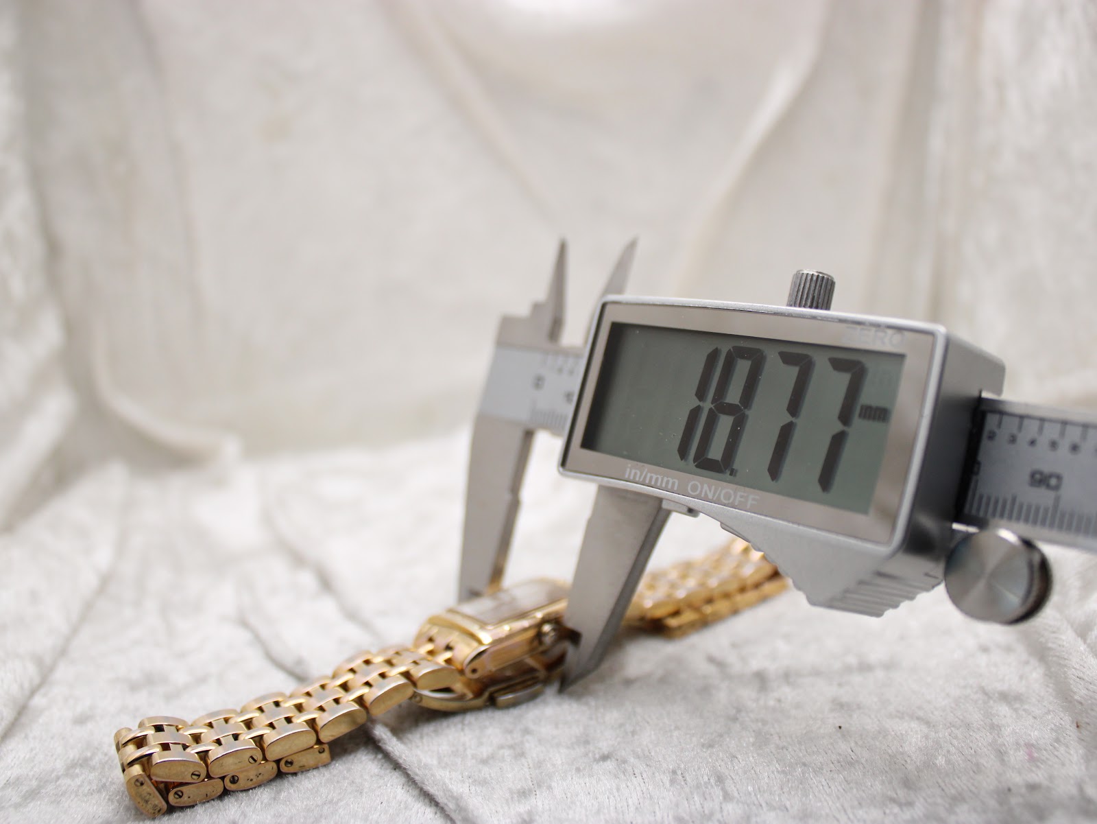 Digital caliper measuring the case diameter of the watch, displaying a precise reading of 18.77mm.
