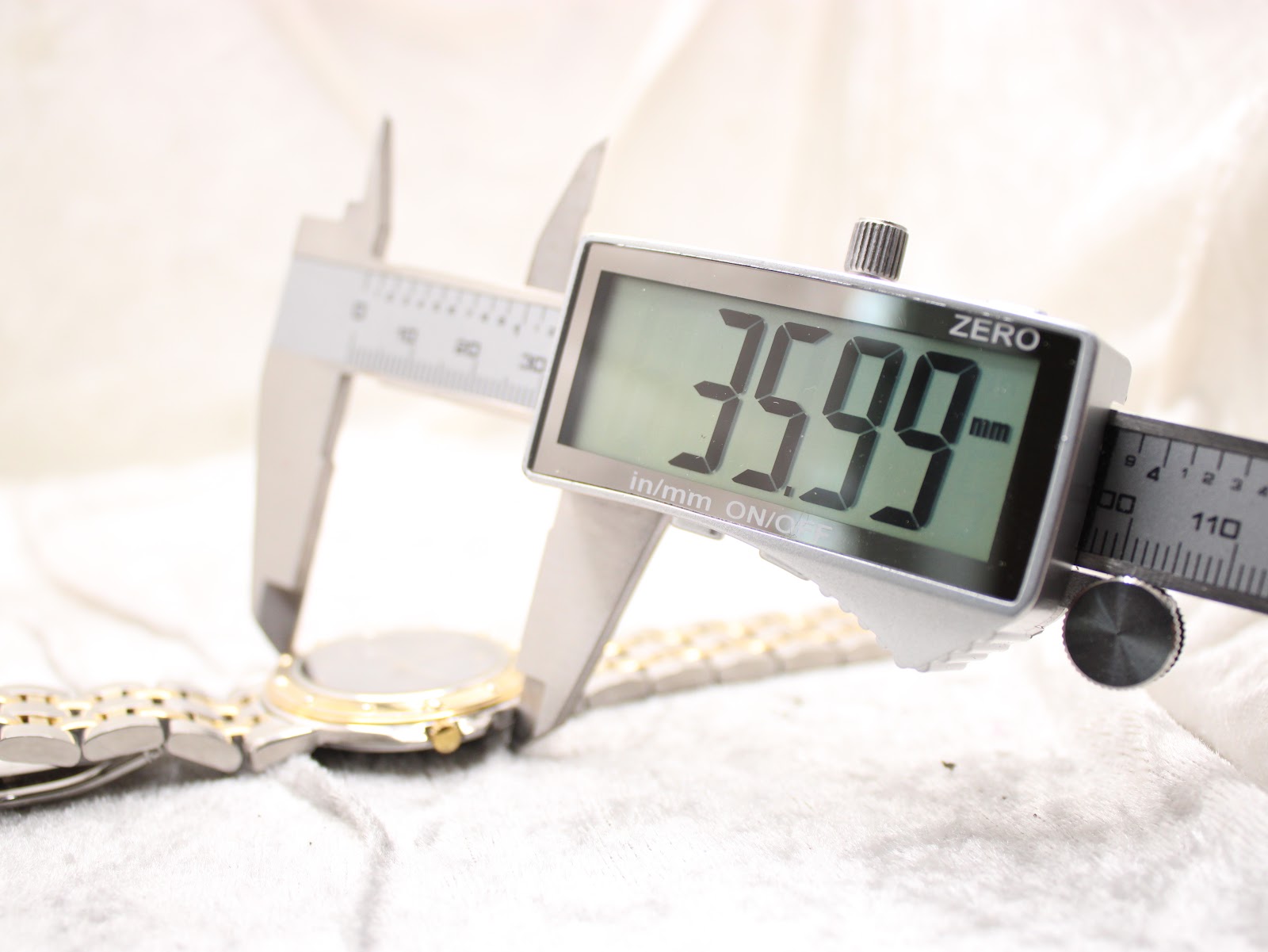Digital caliper measuring the watch case diameter at 35.99 mm, highlighting the two-tone bezel.