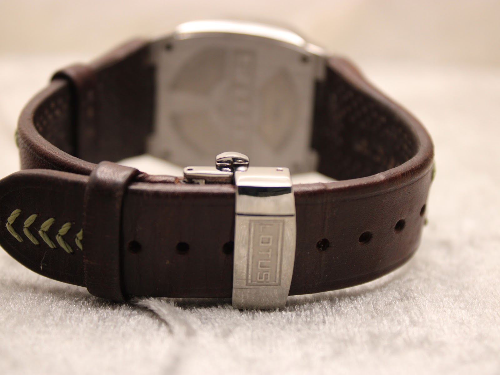 Rear view of the watch, showing the Lotus branded deployant clasp in its closed position, securing the brown leather strap.