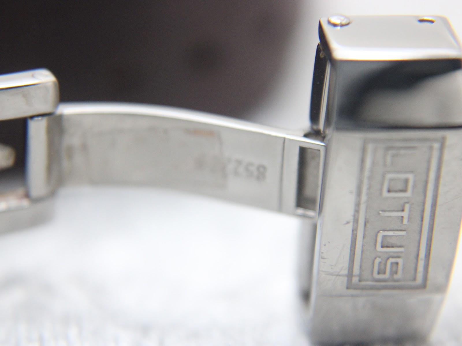 Close-up of the interior of the open Lotus branded deployant clasp, made of stainless steel.