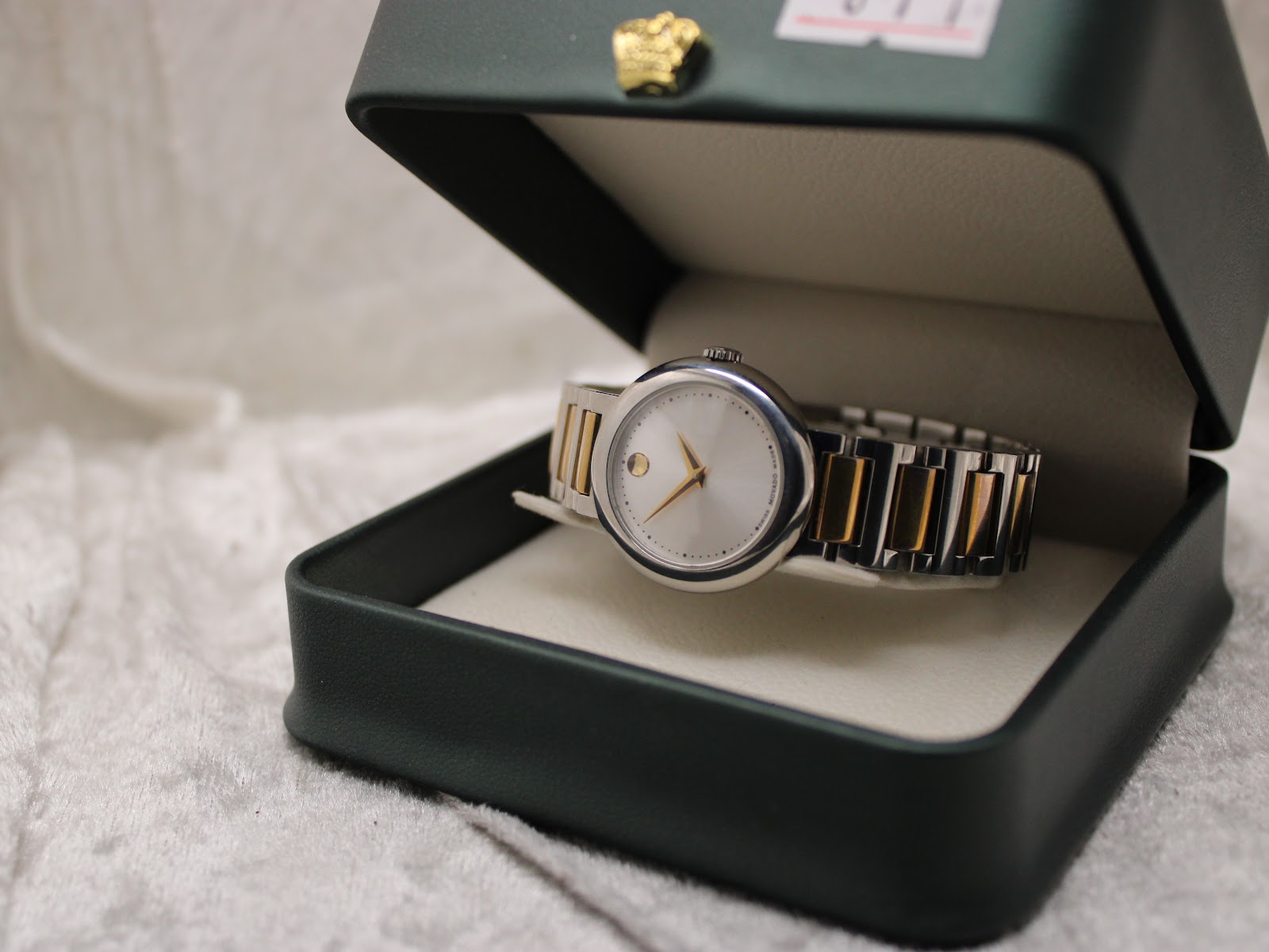 Movado Concerto watch resting inside its original dark green presentation box with gold crown detail.