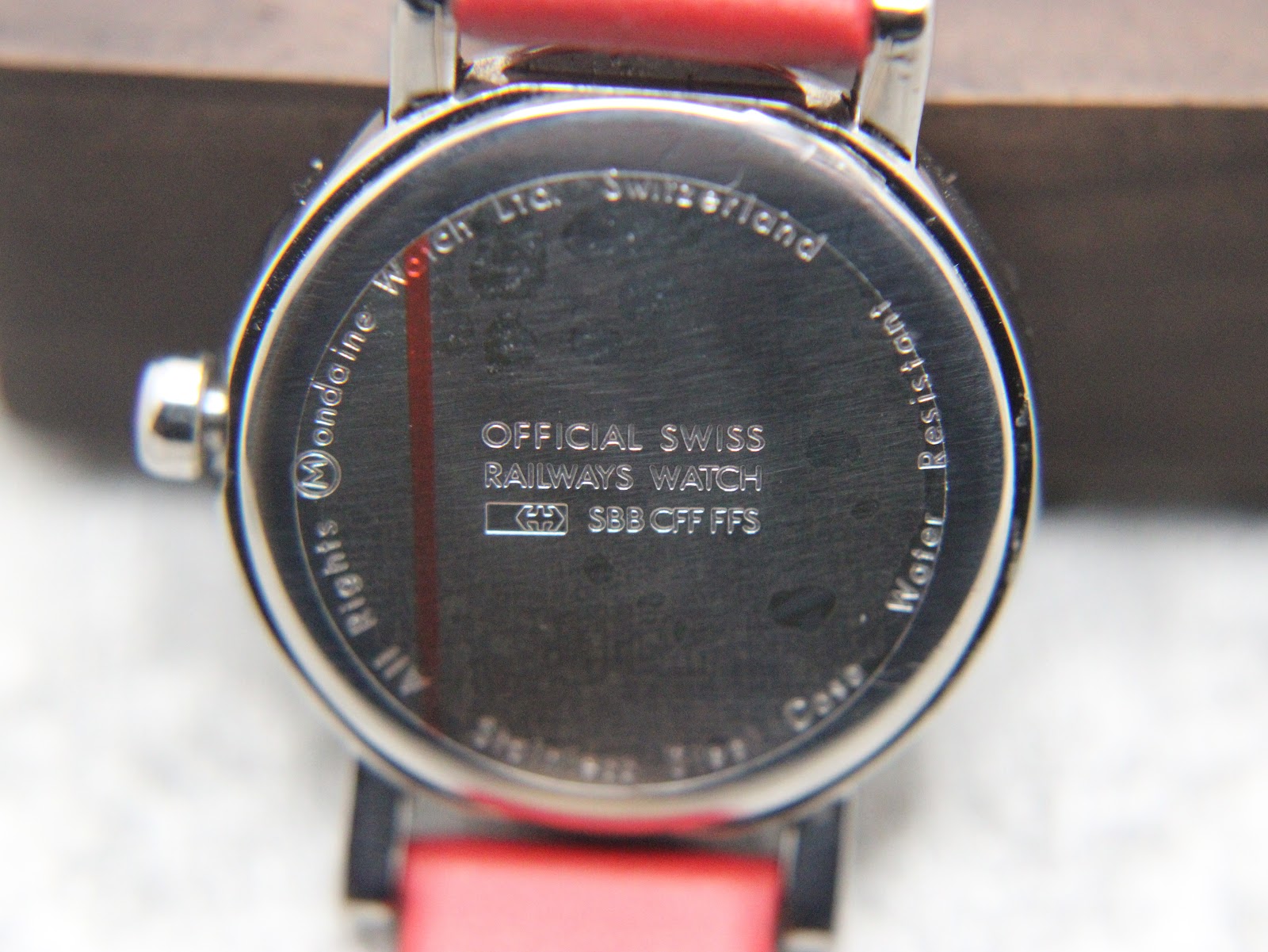 Close-up of the watch case back, with engravings for Mondaine Watch Ltd., Switzerland, Official Swiss Railways Watch, Stainless Steel Case, and Water Resistant.