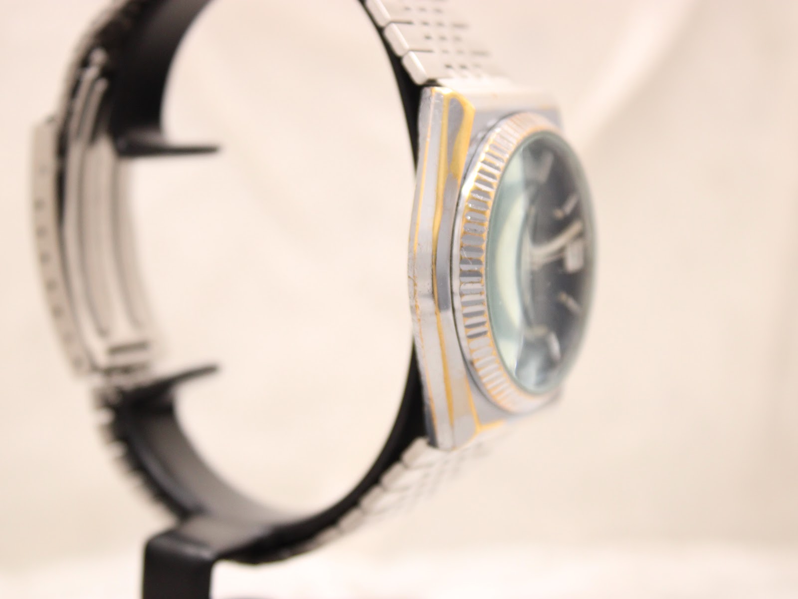 Opposite side profile of the watch case, showing the integrated bracelet connection and bezel edge wear.