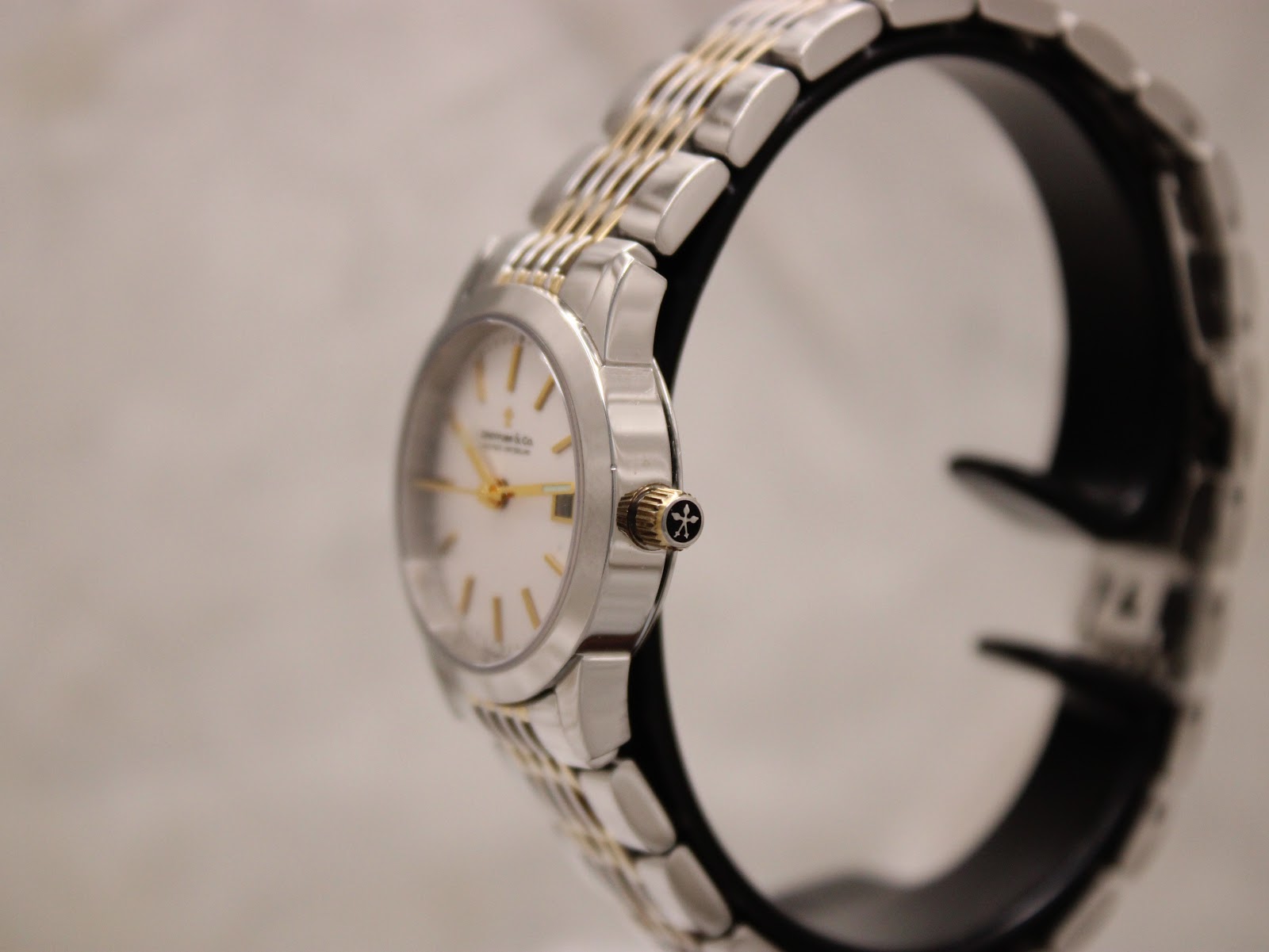 Side profile view of the Dreyfuss & Co watch, showing the silver case and gold-toned signed crown on a display stand.