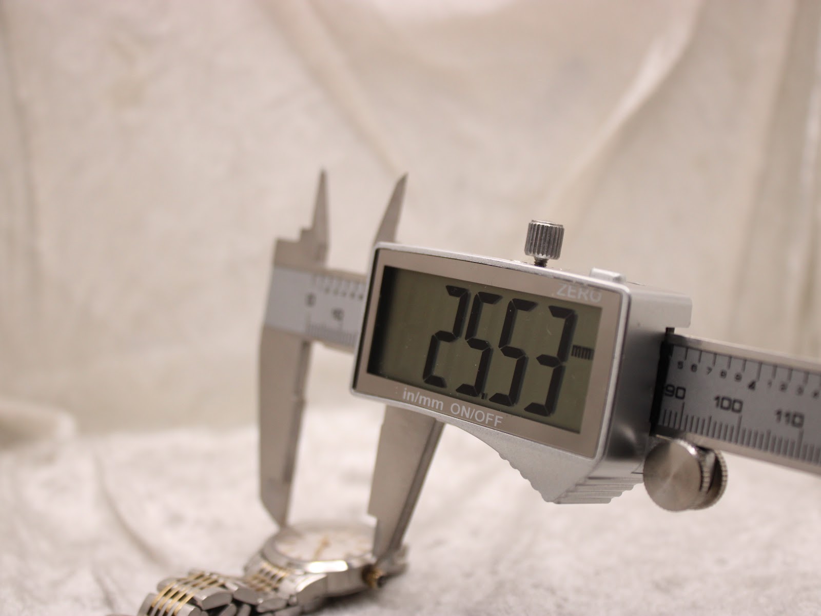 Digital caliper measuring the watch case diameter, displaying a precise reading of 25.53mm.