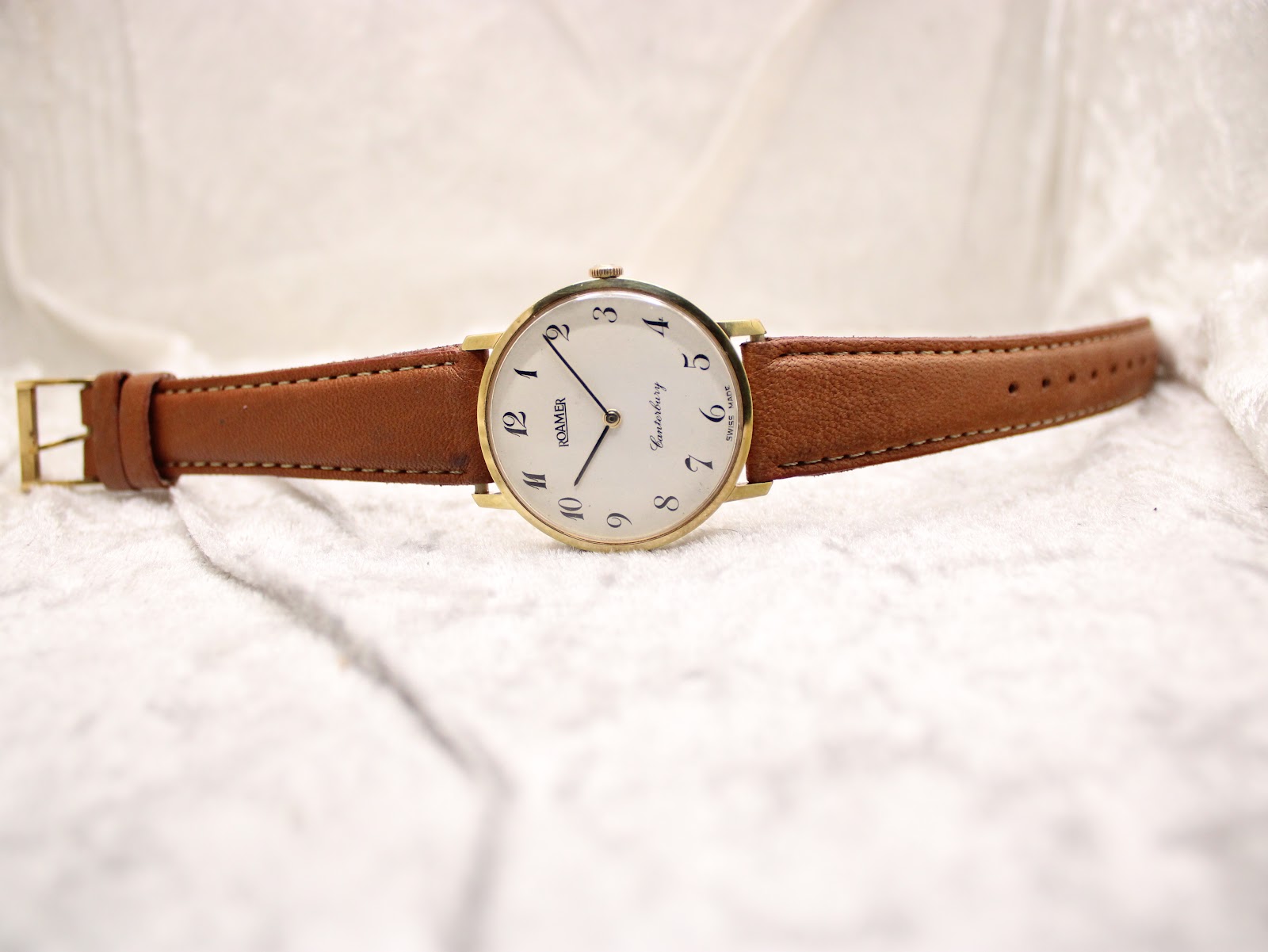 Full front view of the Roamer Canterbury watch with a light brown leather strap laid out on a white textured surface.