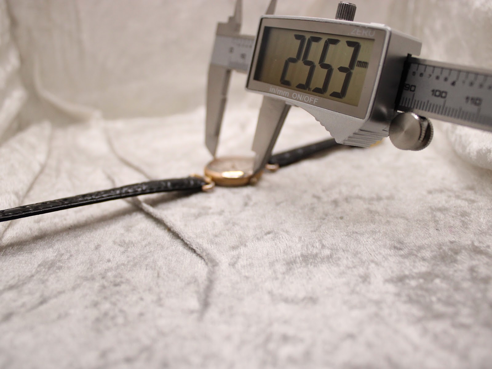 Digital caliper measuring the case diameter of the Rotary watch, displaying a precise measurement of 25.53 mm on the screen.