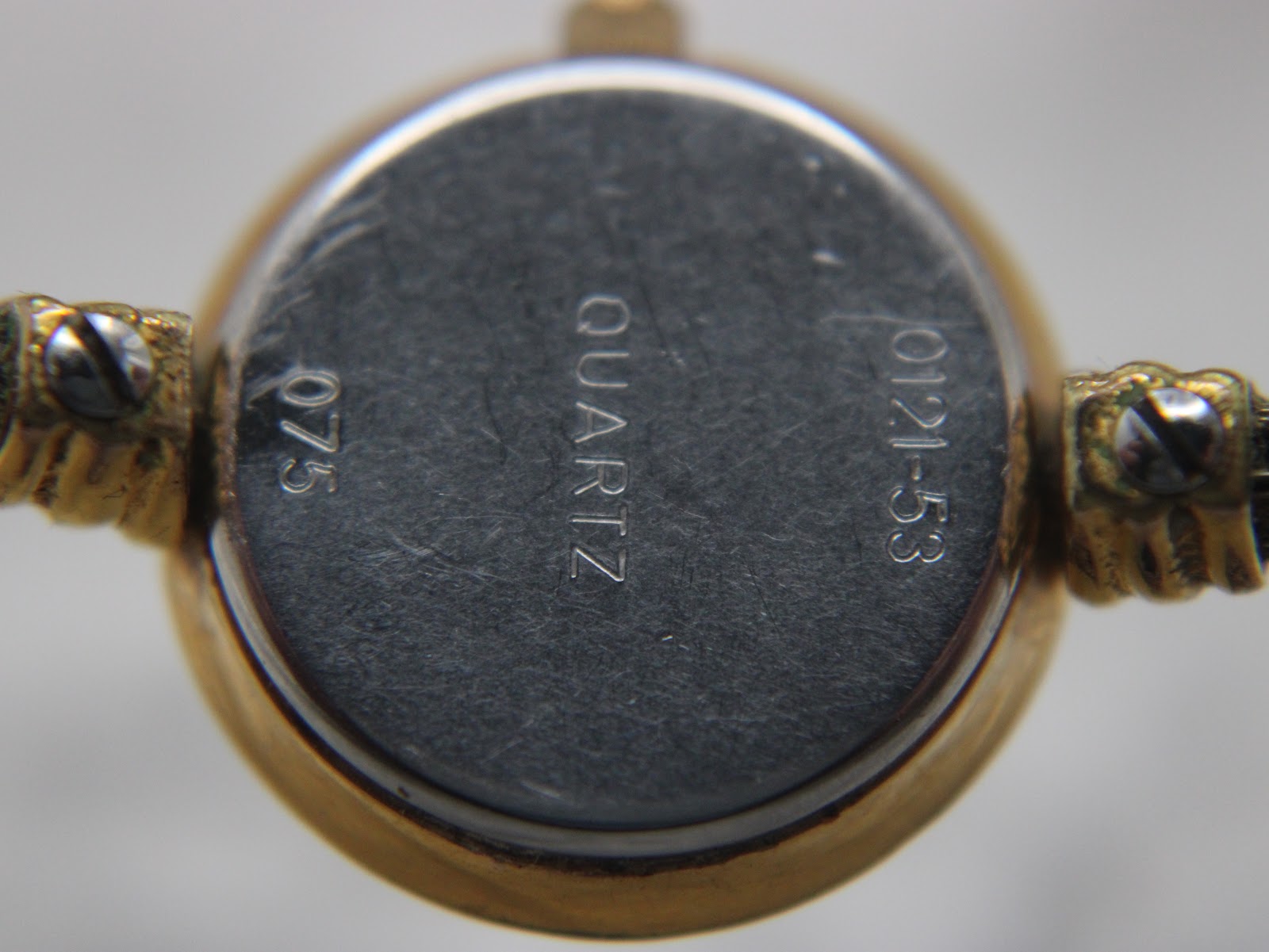 Close-up of the watch's case back, engraved with "QUARTZ", "0121-53", and "075".